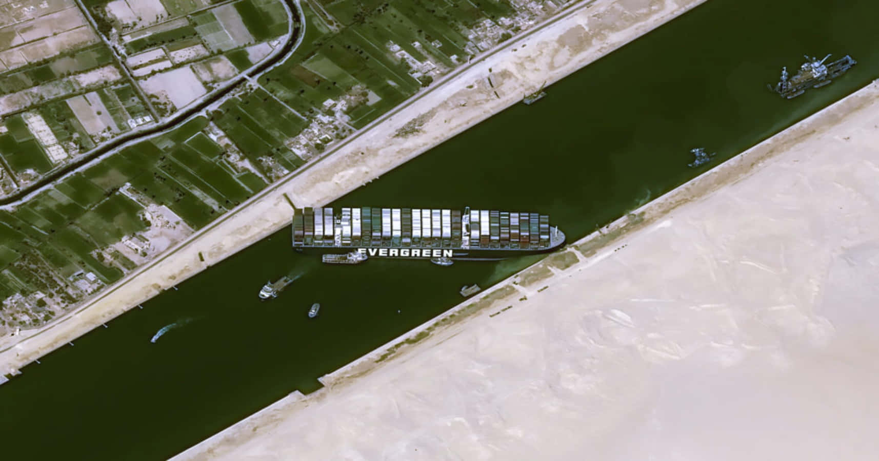 Cargo Ship 桌布 壁紙 — 從高空俯瞰巨大的長榮貨櫃船在狹窄的蘇伊士運河航行，兩旁是沙漠和農田。