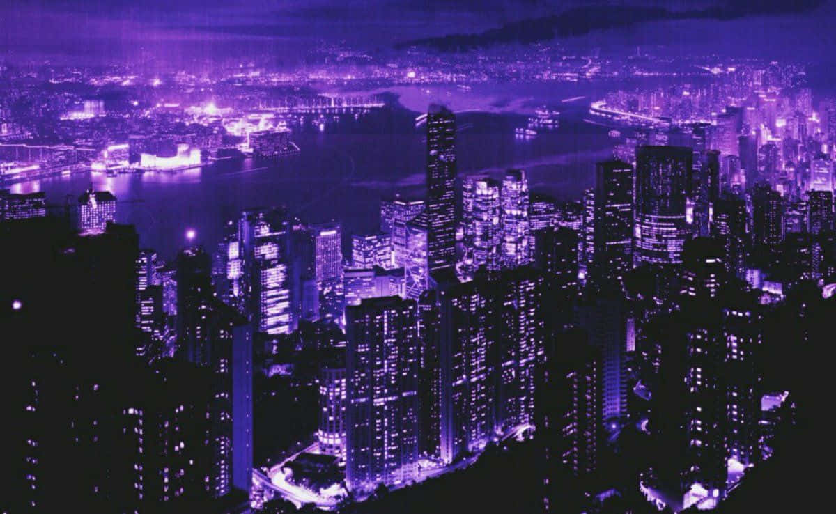 Purple Aesthetic Laptop 桌布 壁紙 — 從高空俯瞰廣闊的城市夜景，無數發光的窗戶和街燈散發出充滿活力的紫色光芒。