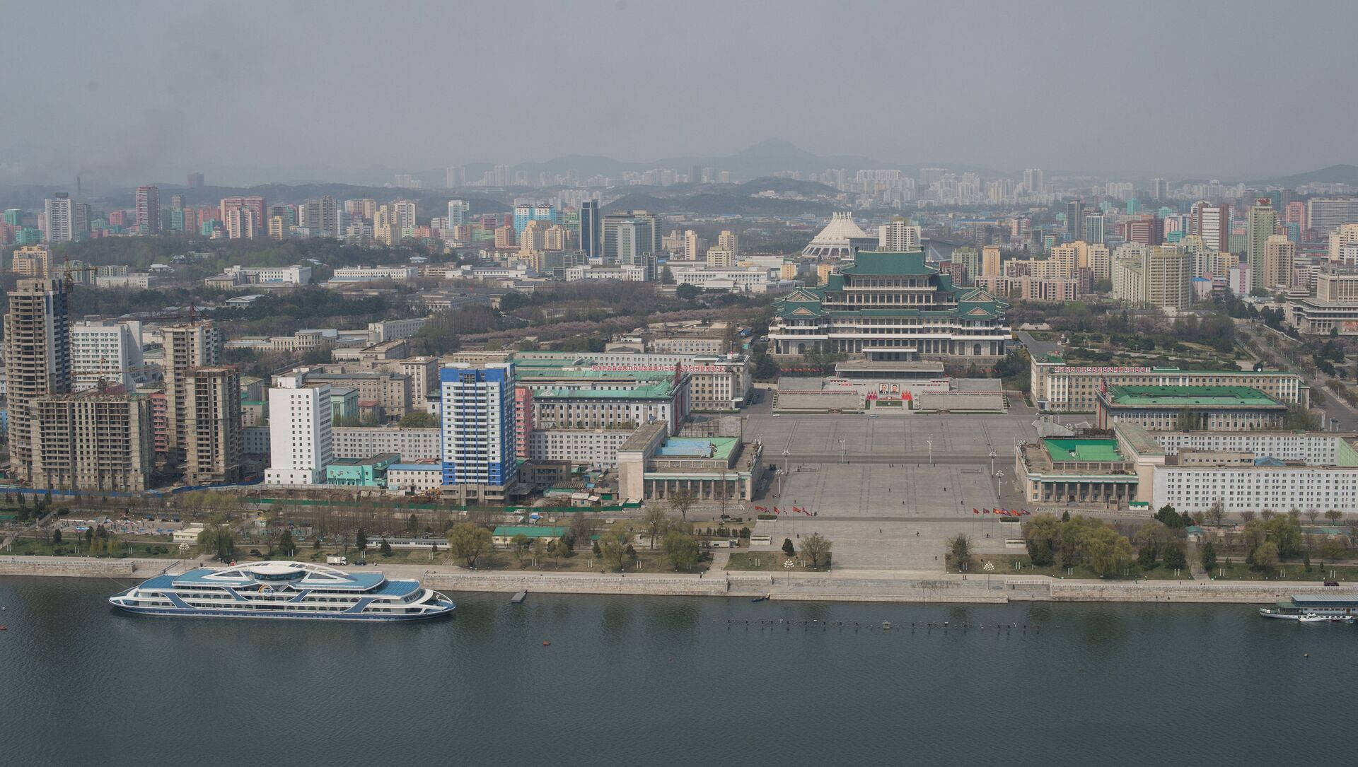 韓國 桌布 壁紙 — 從高空俯瞰廣闊的城市景觀，有一條寬闊的河流和一艘大船在朦朧的天空下航行。