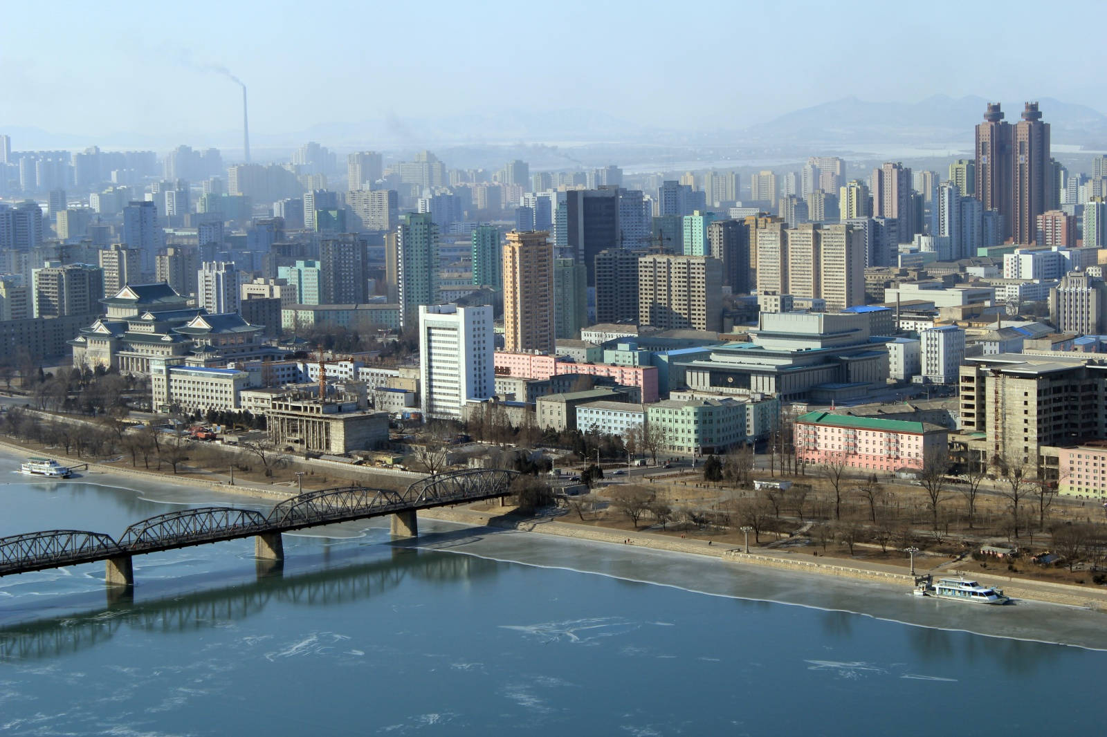 韓國 桌布 壁紙 — 從高空俯瞰廣闊的城市景觀，河流部分結冰，橋樑橫跨水面，現代建築在朦朧的天空下。