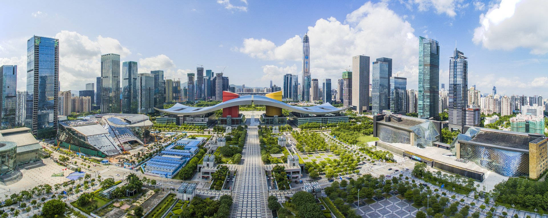 中國 桌布 壁紙 — 從高空俯瞰未來城市景觀，玻璃摩天大樓、綠色公園和寬闊廣場，在藍天白雲下展現。