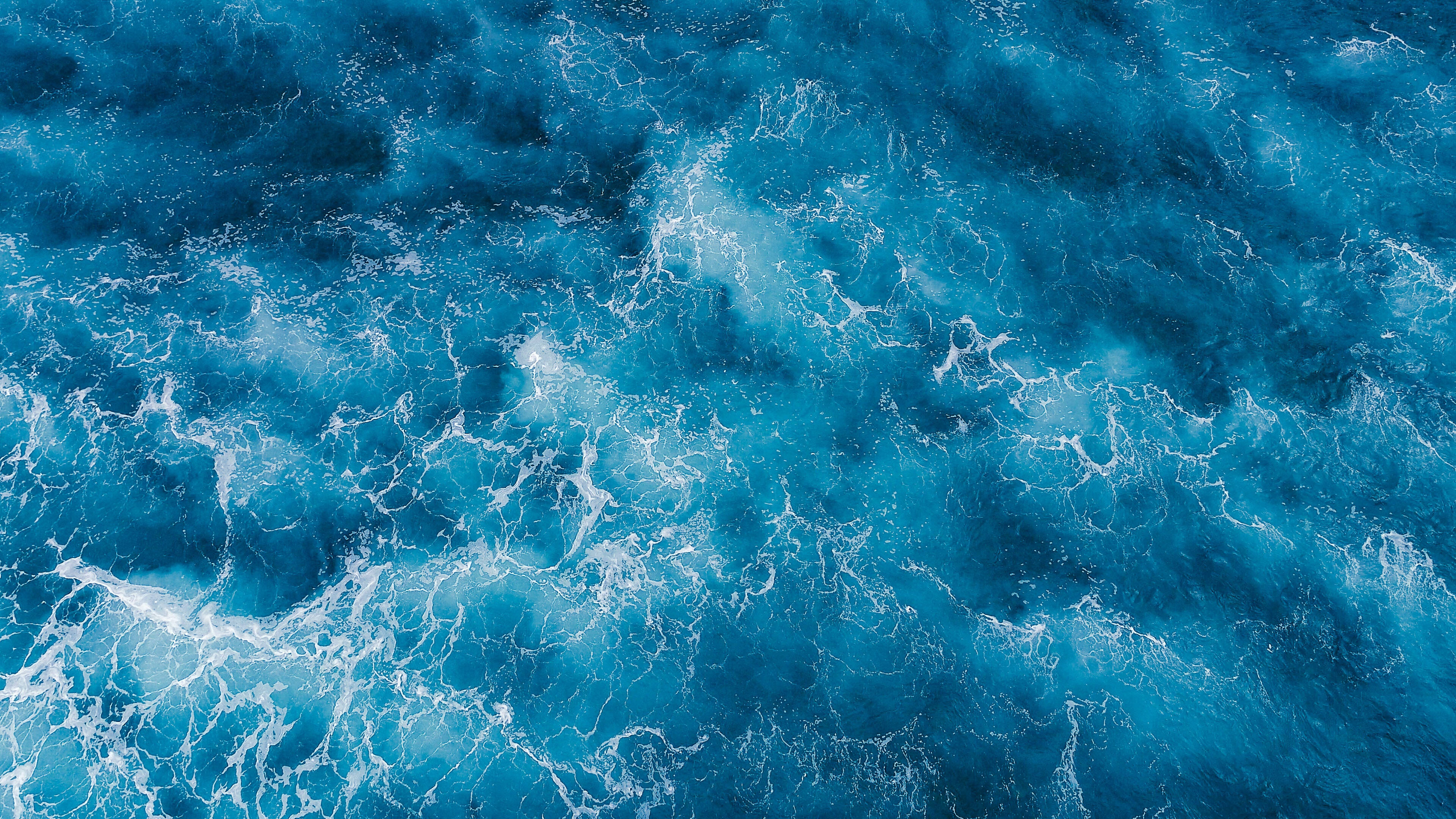 Beautiful Sea 桌布 壁紙 — 從高空俯瞰洶湧的海浪，深藍色的海水與泡沫般的白色浪花在混亂的運動中旋轉。