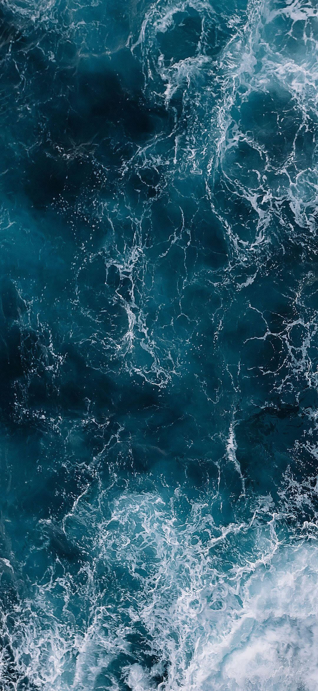水 桌布 壁紙 — 從高空俯瞰洶湧的深藍色海浪，白色泡沫形成動態漩渦圖案。