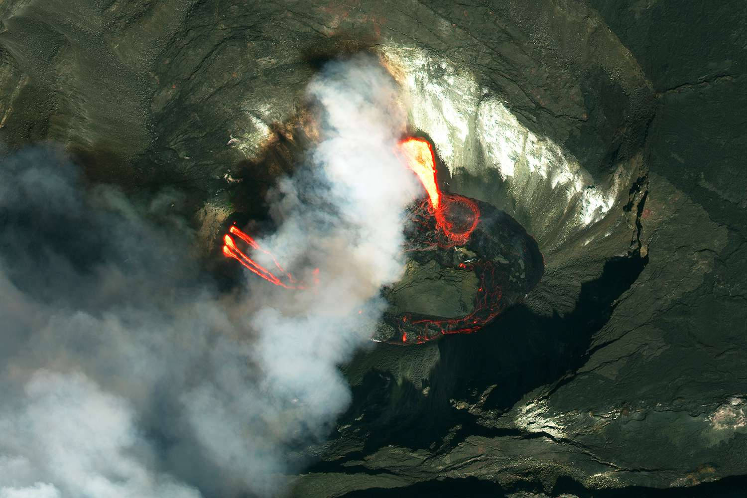 地球 桌布 壁紙 — 從高空俯瞰火山口噴發，發出熾熱熔岩和滾滾濃煙，背景是黑暗崎嶇的地形。