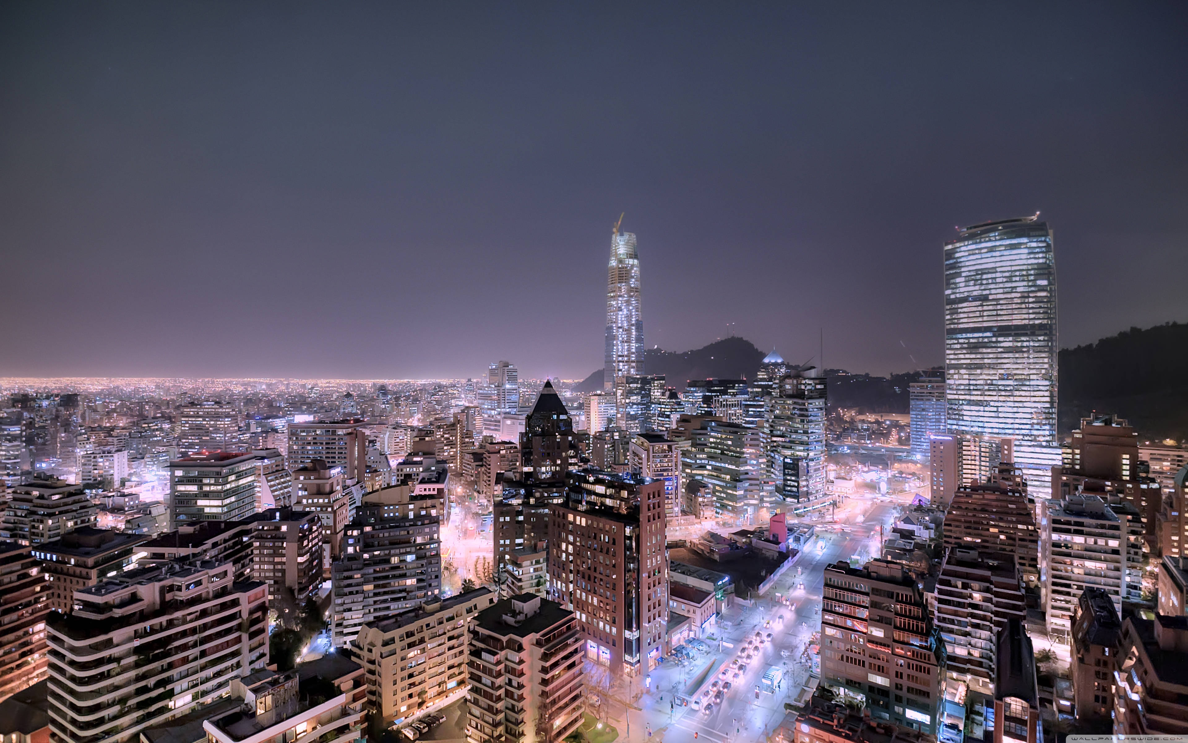 夜空 桌布 壁紙 — 從高空俯瞰的夜景，展現廣闊的城市景觀，摩天大樓閃爍光芒，街道燈火通明，映襯著漆黑的夜空。