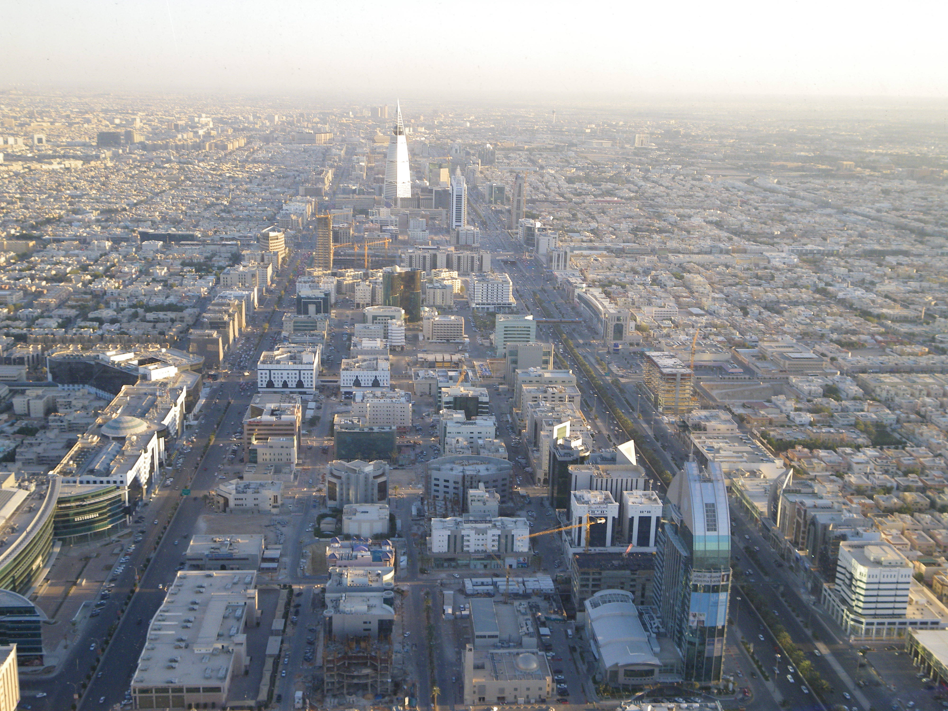 Riyadh 桌布 壁紙 — 從高空俯瞰的現代城市景觀，高聳的摩天大樓和寬闊的大道沐浴在金色的晨光中。