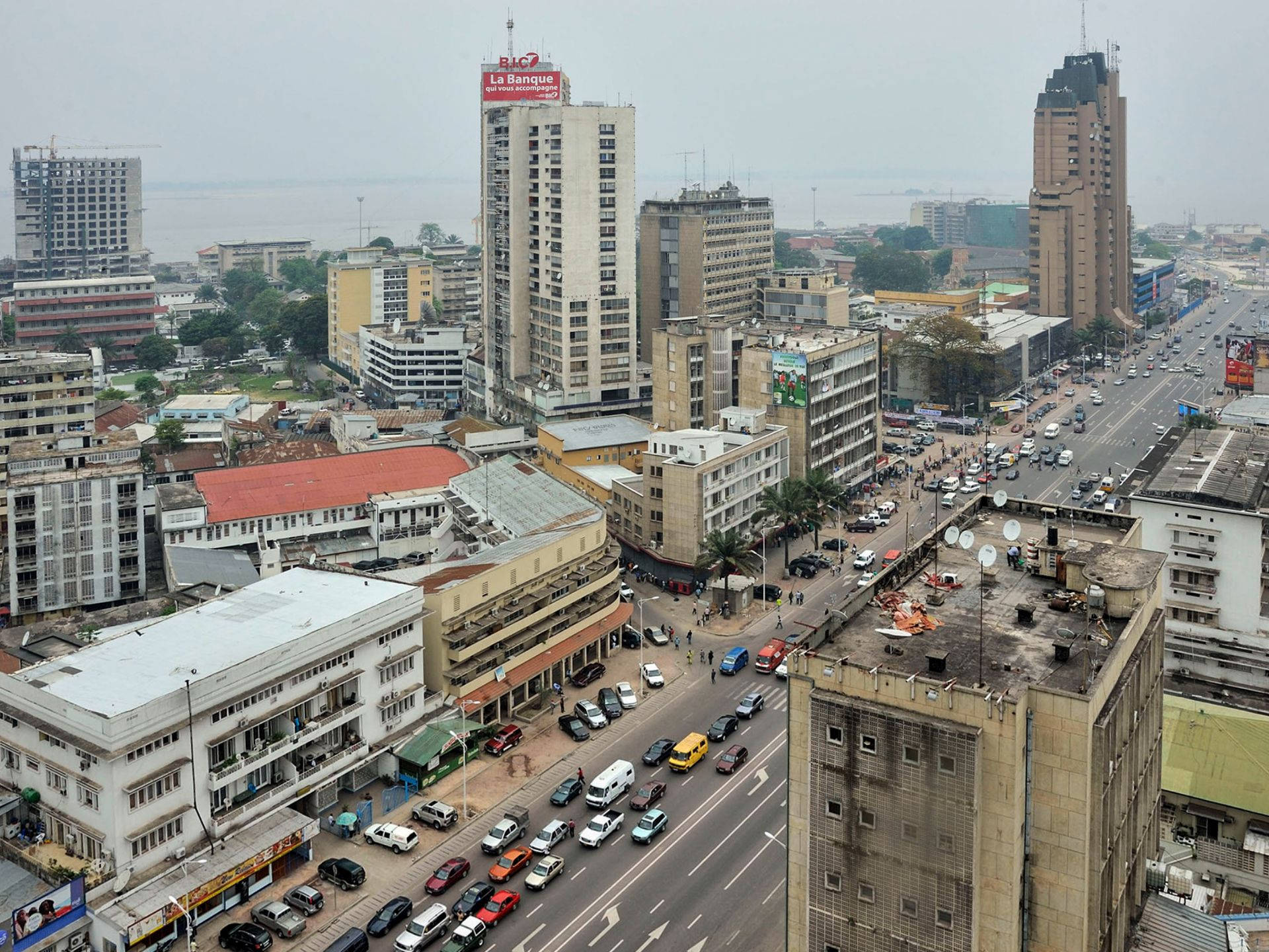 Kinshasa 桌布 壁紙 — 從高空俯瞰繁忙的城市景觀，交通密集，建築風格多樣，天空多雲。