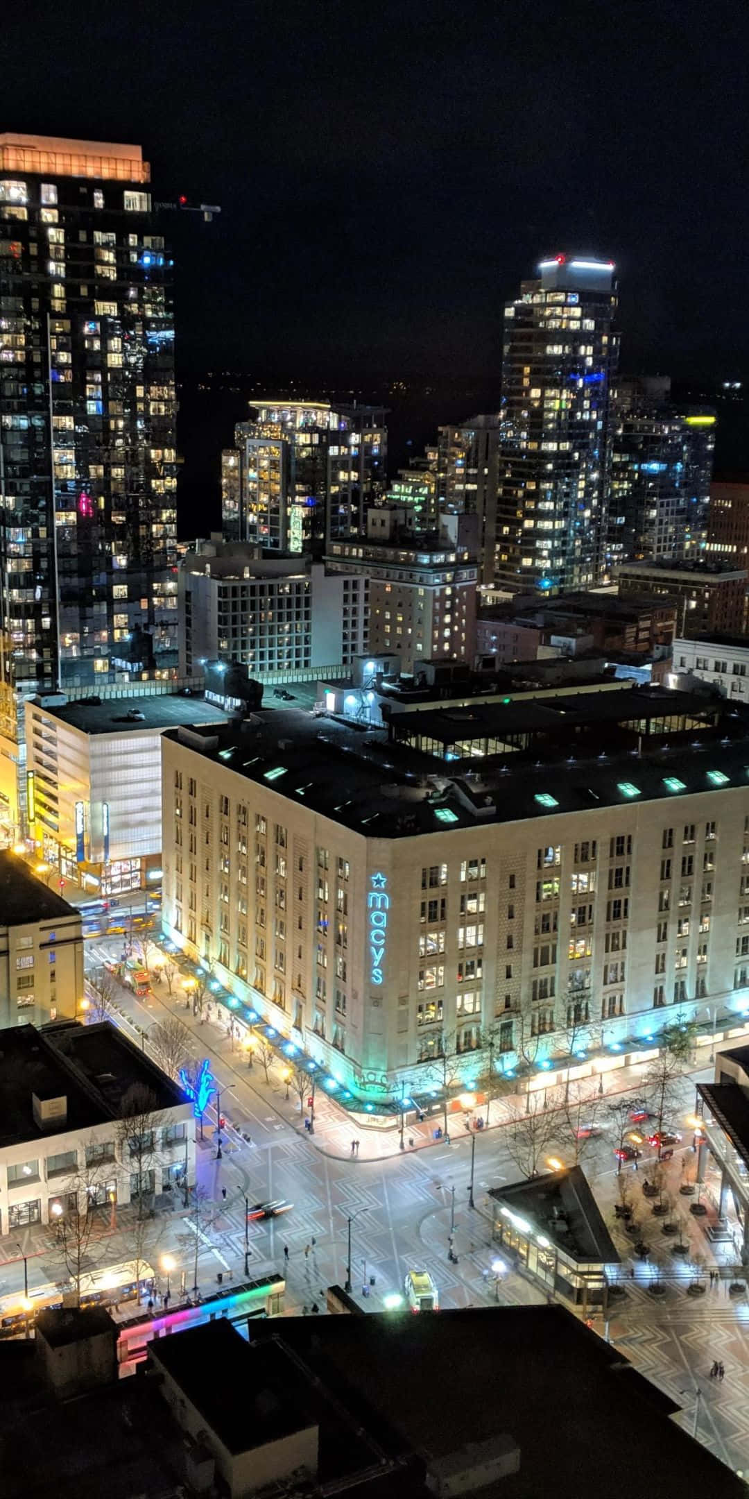 Pixel 3 Seattle 桌布 壁紙 — 從高空俯瞰繁華城市景觀的夜景，燈火通明的摩天大樓和閃耀的Macy's建築位於繁忙的十字路口。