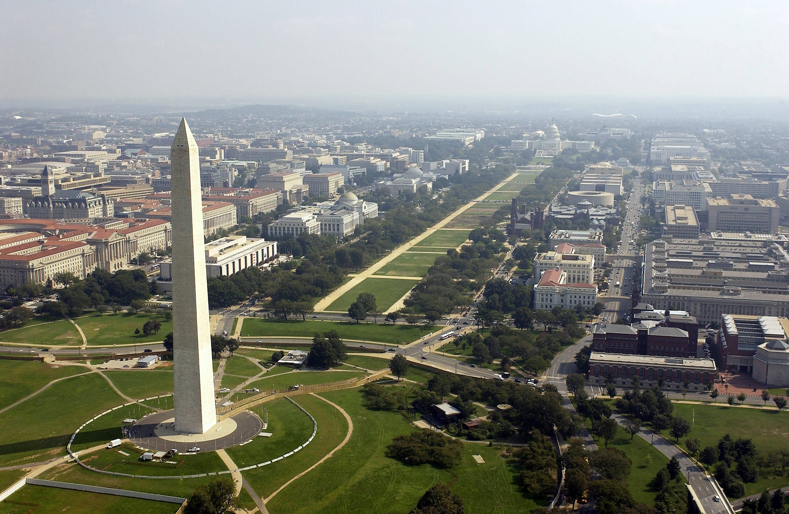 Washington 桌布 壁紙 — 從高空俯瞰華盛頓紀念碑聳立於國家廣場之上，遠處國會大廈在朦朧天空下若隱若現。