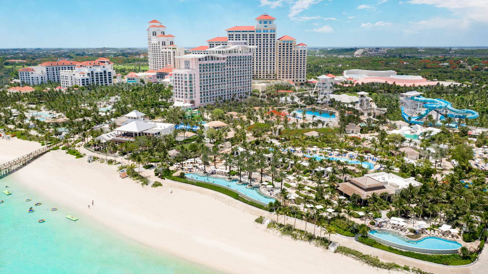 Nassau Bahamas 桌布 壁紙 — 從高空俯瞰豪華海濱度假村，碧綠海水、棕櫚樹和多層建築在清澈藍天下。