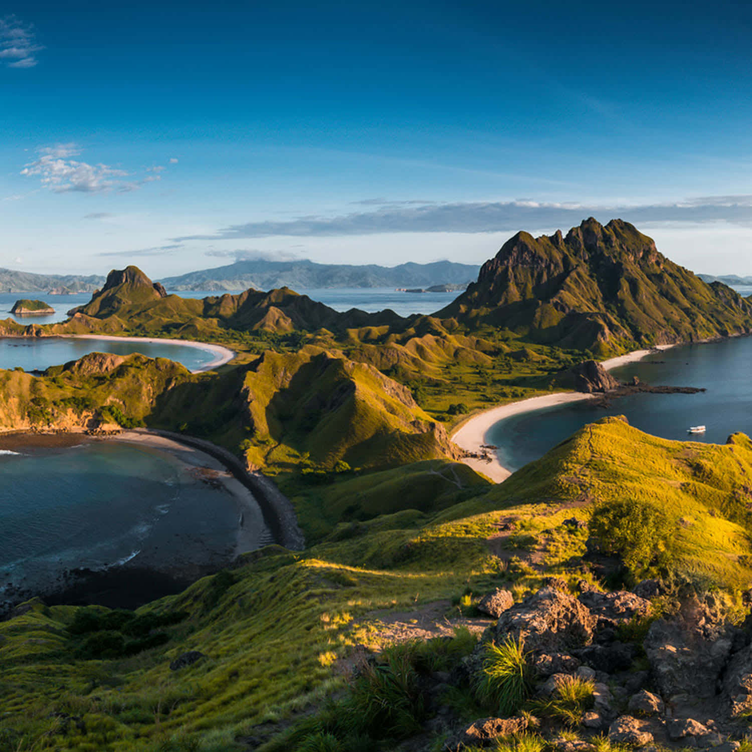 風景 桌布 壁紙 — 從高空俯瞰鬱鬱蔥蔥的綠色火山島，擁有新月形海灘和碧綠海水，在清澈的藍天下。
