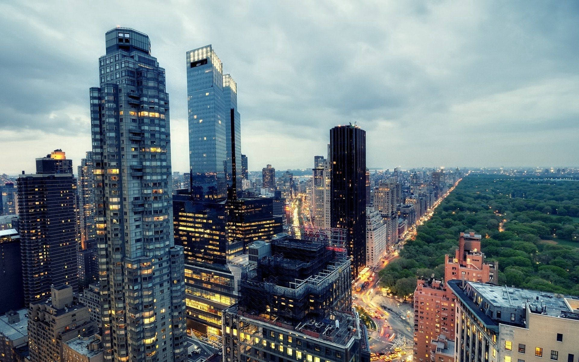 Nyc 桌布 壁紙 — 從高空俯瞰黃昏時分高聳的玻璃摩天大樓和鬱鬱蔥蔥的綠色公園，城市燈光閃爍。