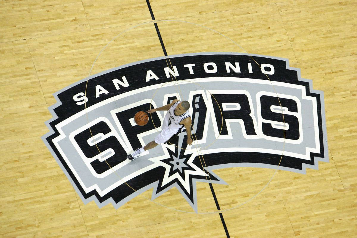 Spurs 桌布 壁紙 — 從高角度俯瞰，一名籃球運動員在木地板上靠近聖安東尼奧馬刺隊標誌處運球。
