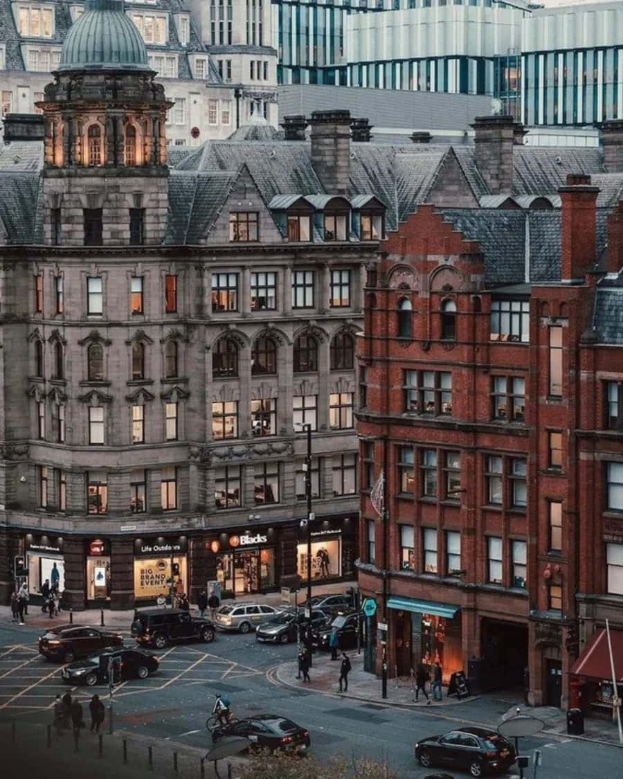 England 桌布 壁紙 — 從高角度俯瞰黃昏時分繁忙的城市街道，歷史悠久的磚石建築、發光的窗戶和行人。