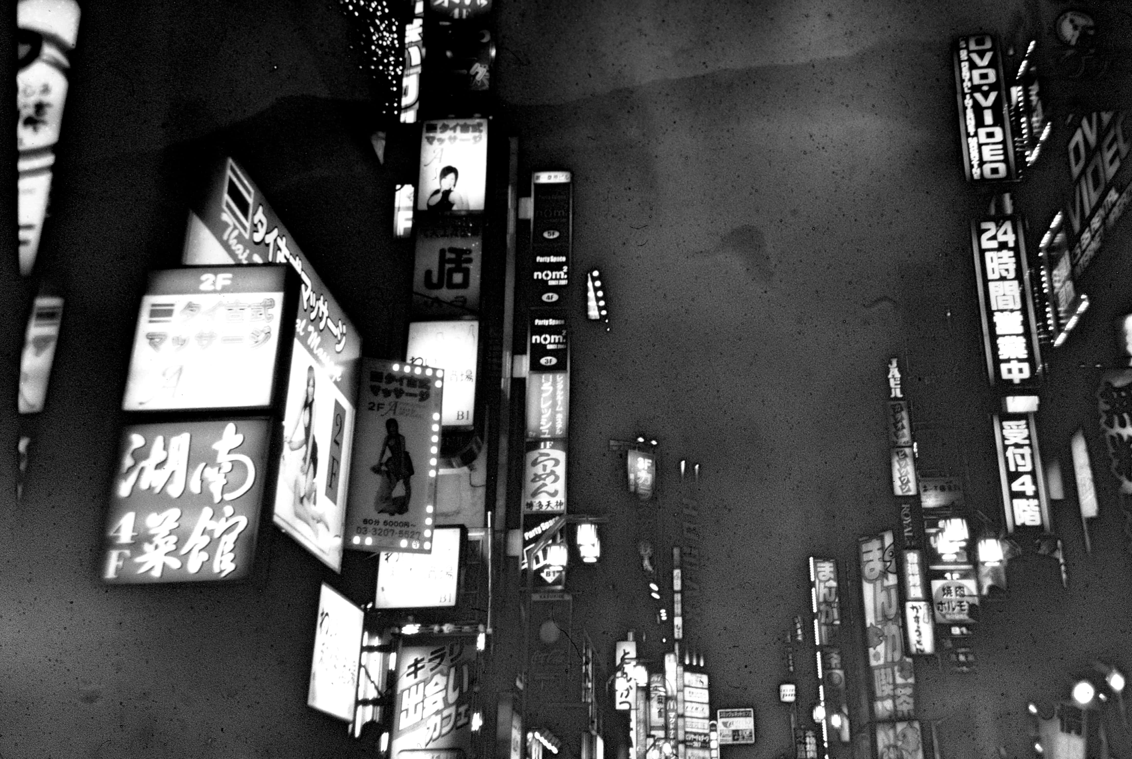 Signs 桌布 壁紙 — 從高角度拍攝的東京繁華霓虹街道夜間黑白照片，帶有發光招牌和密集的城市建築。