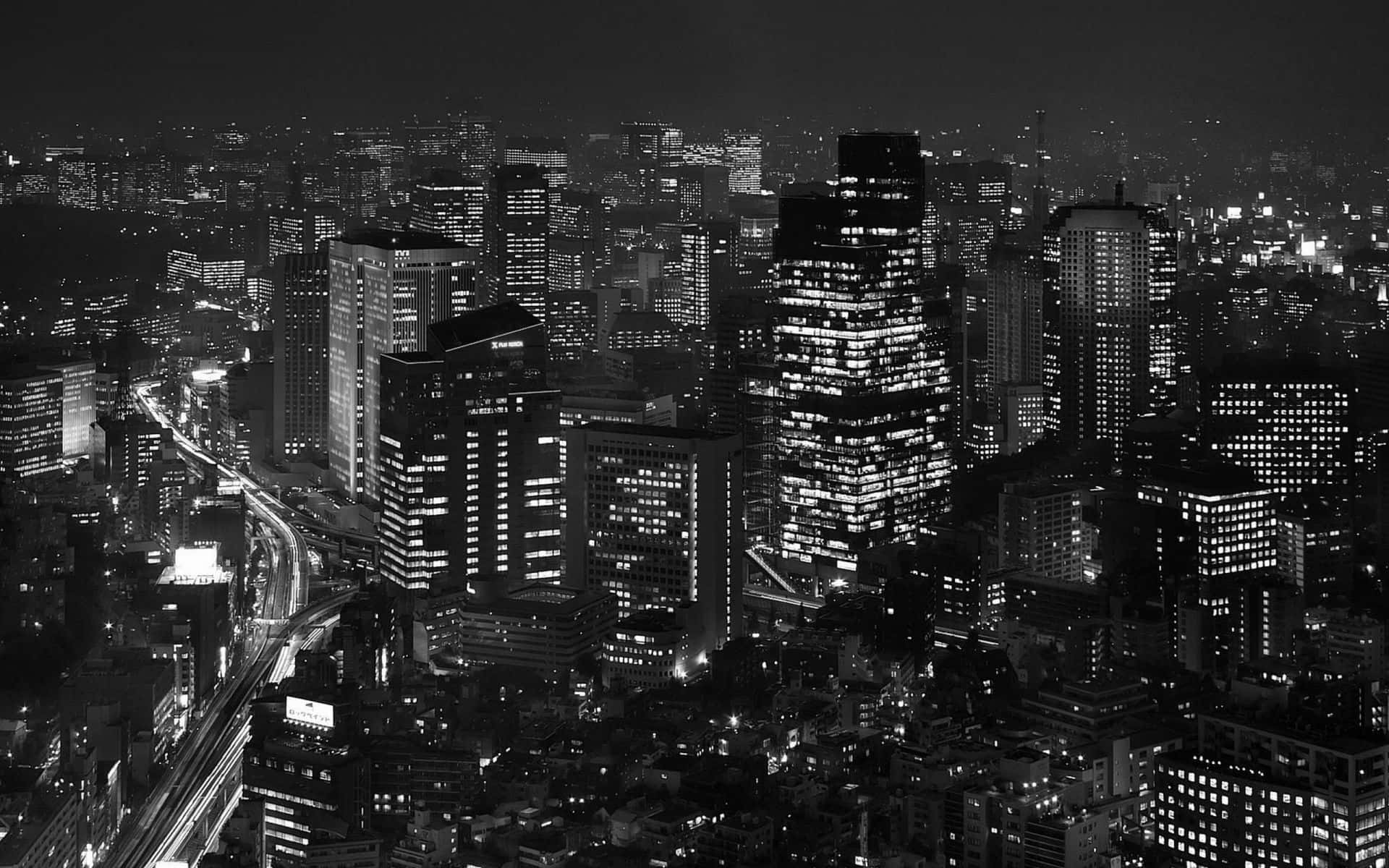 東京 桌布 壁紙 — 從高角度拍攝的黑白夜景，密集的城市天際線，窗戶發光，城市燈光形成條紋。