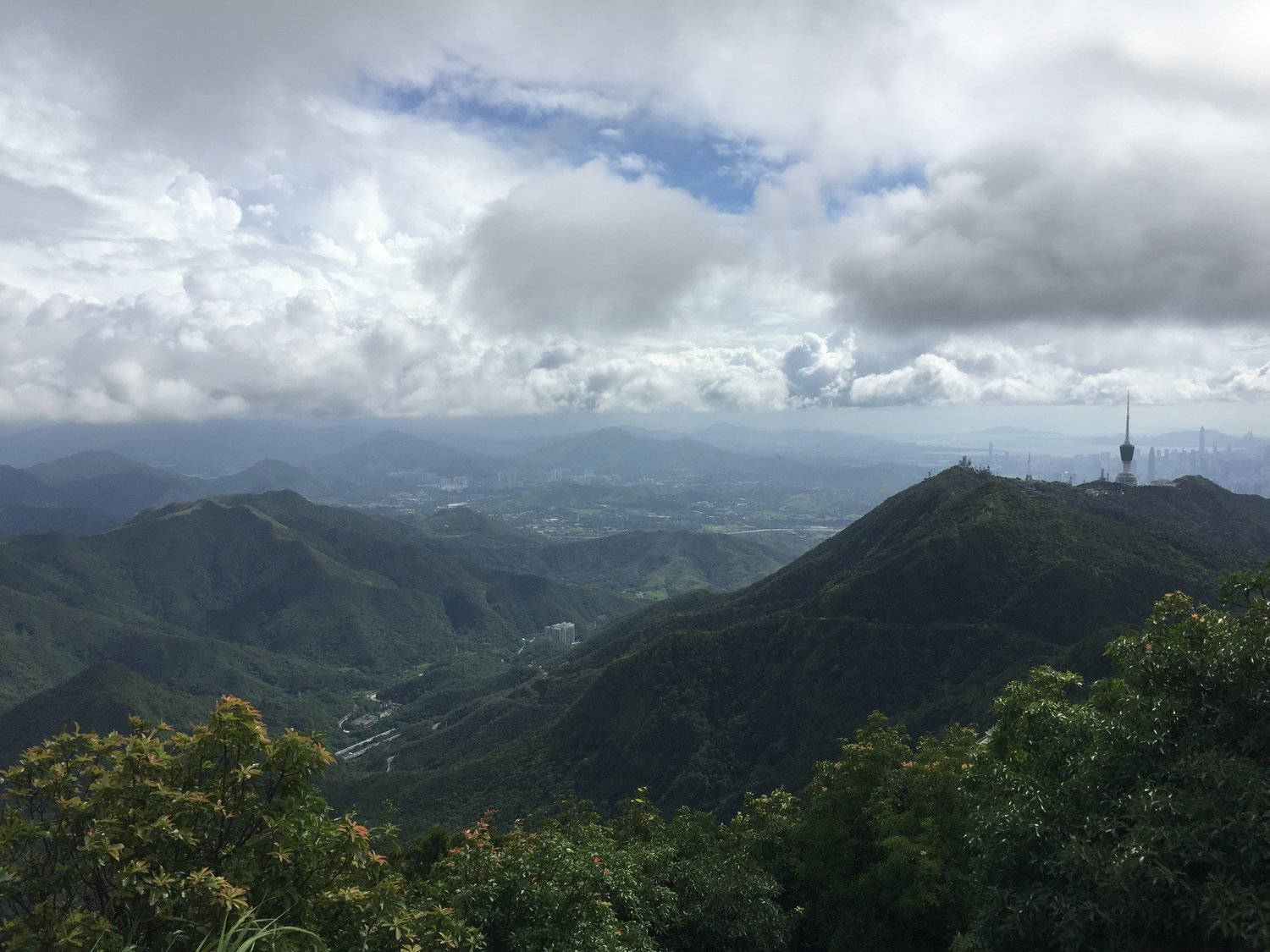 Shenzhen 桌布 壁紙 — 從鬱鬱蔥蔥的綠色山脊俯瞰廣闊的城市景觀，在戲劇性的多雲天空下。