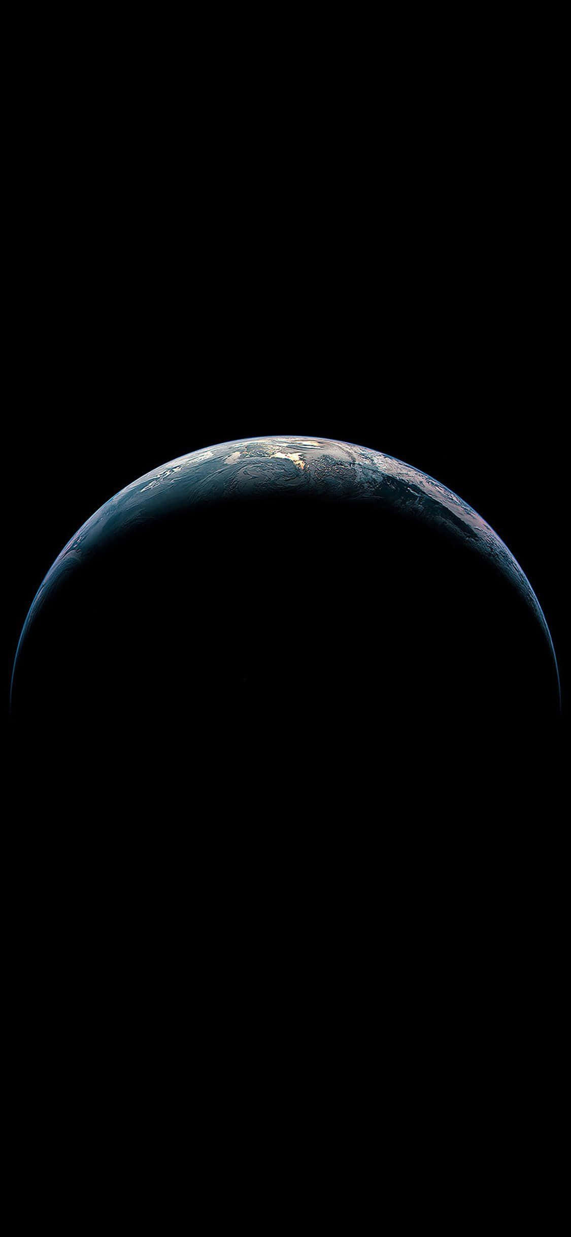 apple iPhone default 桌布 壁紙 — 從黑暗中升起的地球令人驚嘆的景色，沿著彎曲的地平線閃爍著城市燈光。