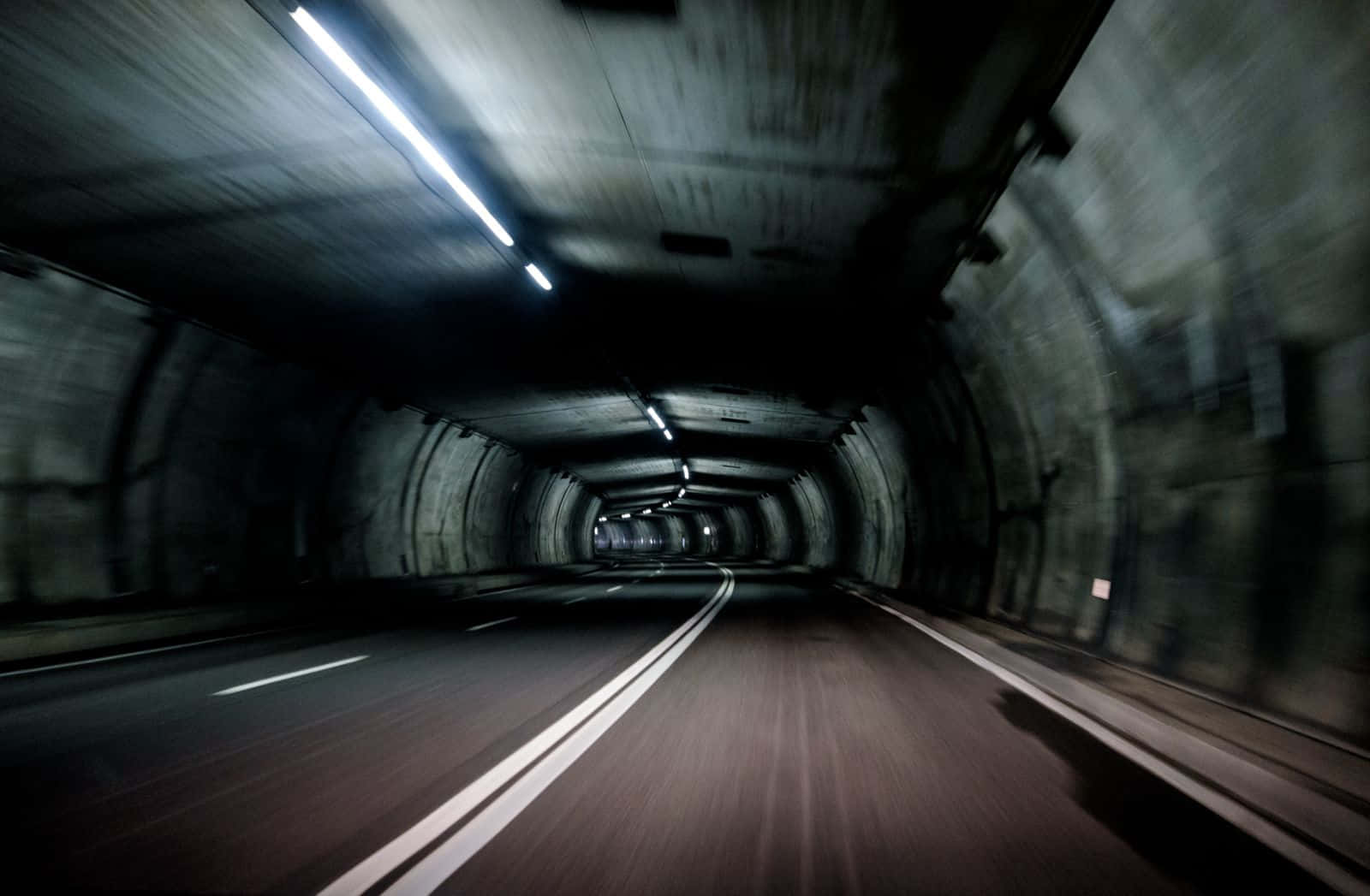 Dark Road 桌布 壁紙 — 從黑暗混凝土隧道內部拍攝的高速動態模糊照片，發光的頂燈逐漸消失在遠方。