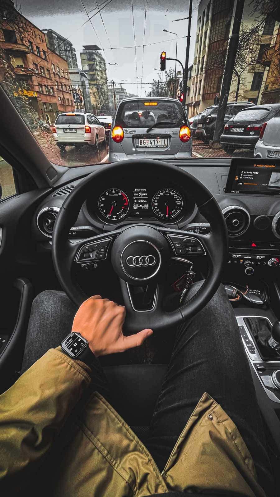 奧迪 桌布 壁紙 — 從黑色奧迪車內以第一人稱視角行駛在潮濕路面和交通燈的雨中城市街道。