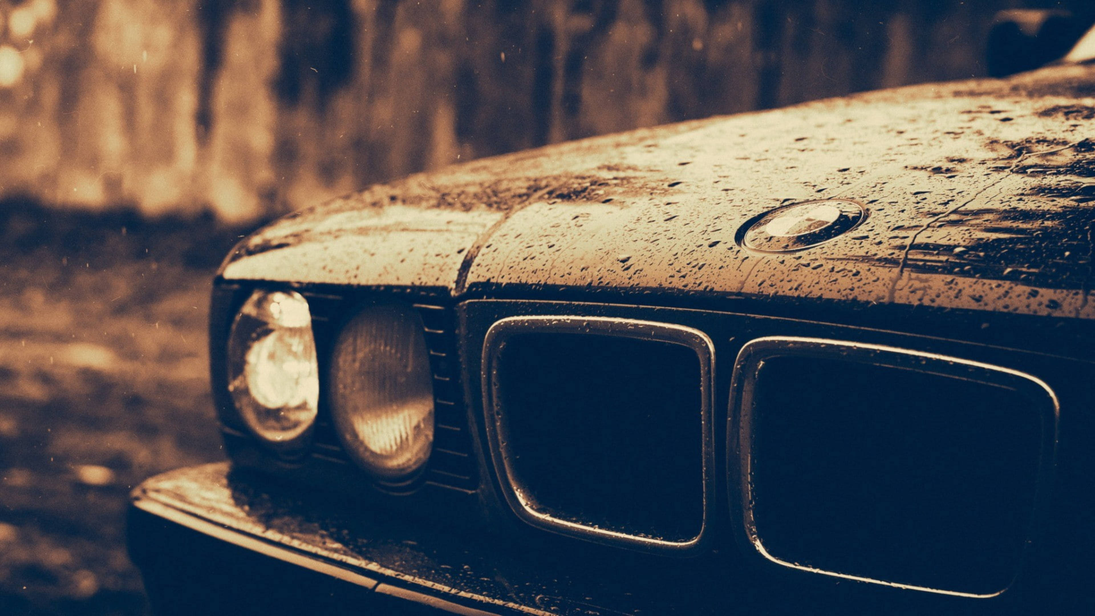BMW 動圖 桌布 壁紙 — 復古BMW汽車引擎蓋在溫暖的懷舊棕色燈光下閃爍著雨滴的特寫。