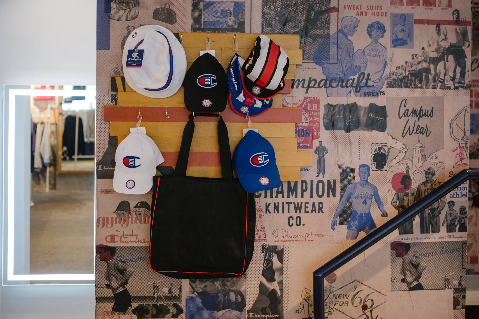 Champion 桌布 壁紙 — 復古Champion品牌帽子展示，搭配復古運動海報和一個黑色托特包掛在木架上。