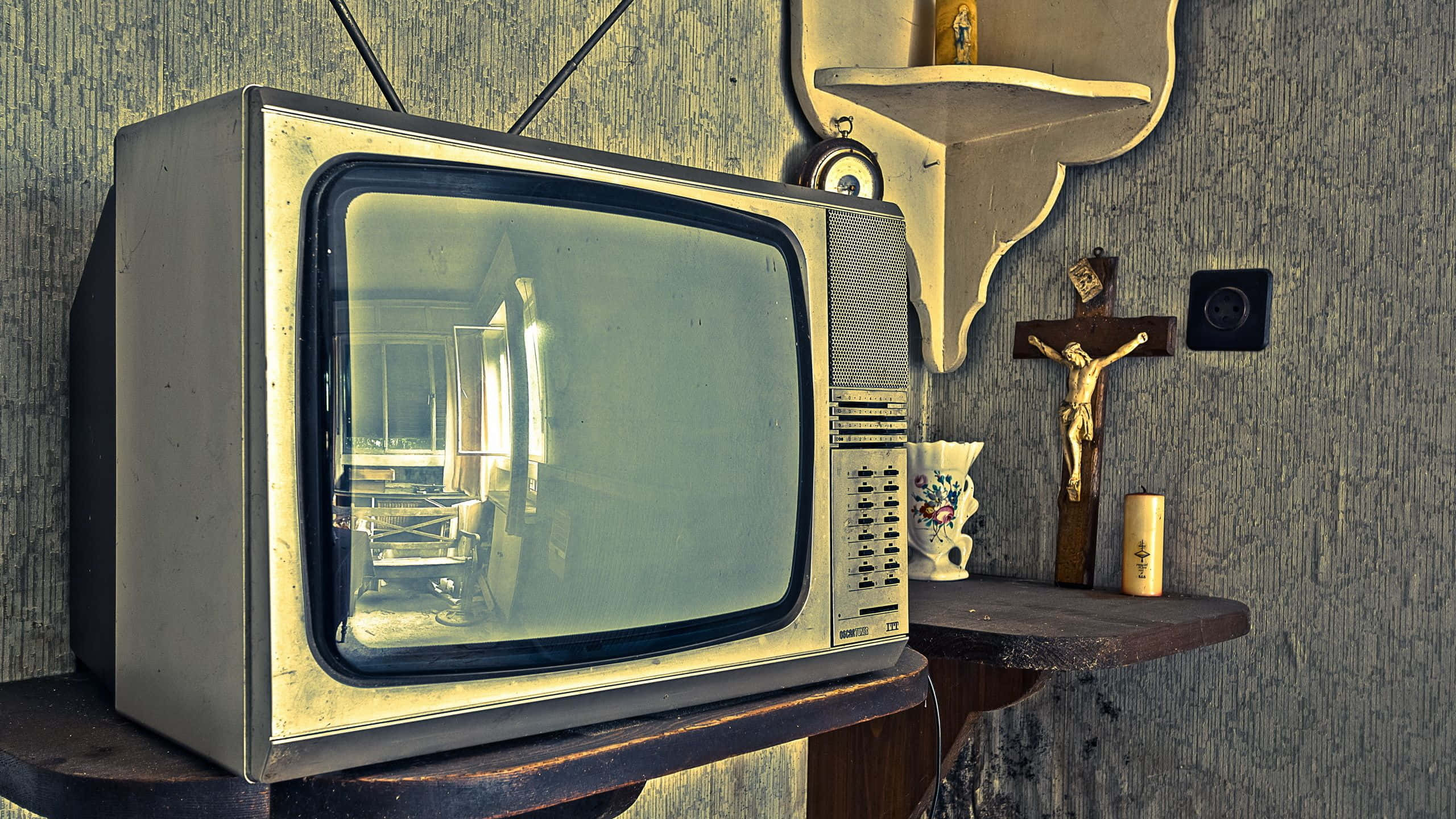 tv 桌布 壁紙 — 復古CRT電視機放在木製底座上，旁邊有十字架和陶瓷杯，背景是紋理牆壁。