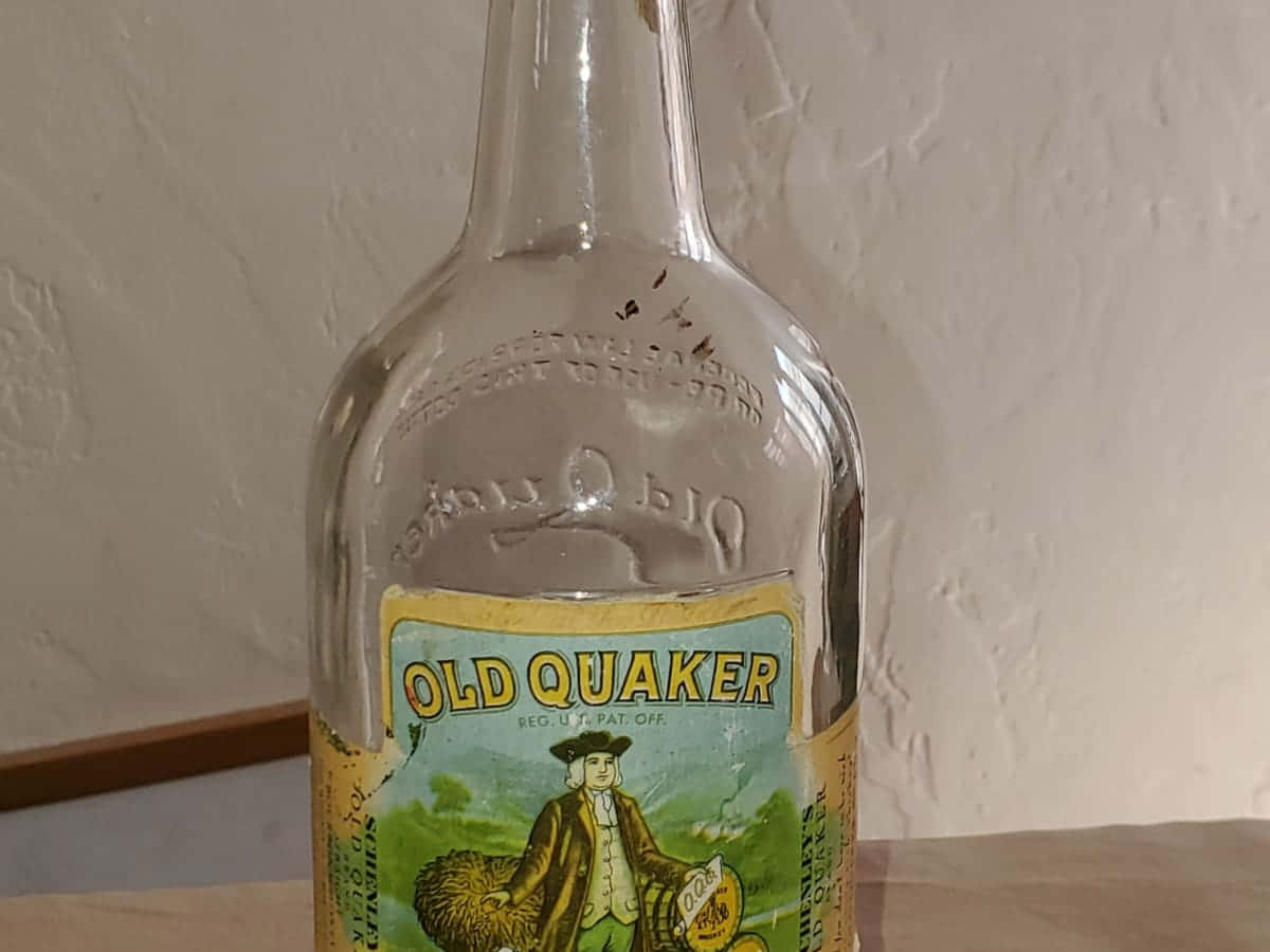Old Bottles 桌布 壁紙 — 復古Old Quaker威士忌酒瓶，帶有浮雕玻璃和彩色標籤，上面有一個拿著玉米的殖民時期男子。