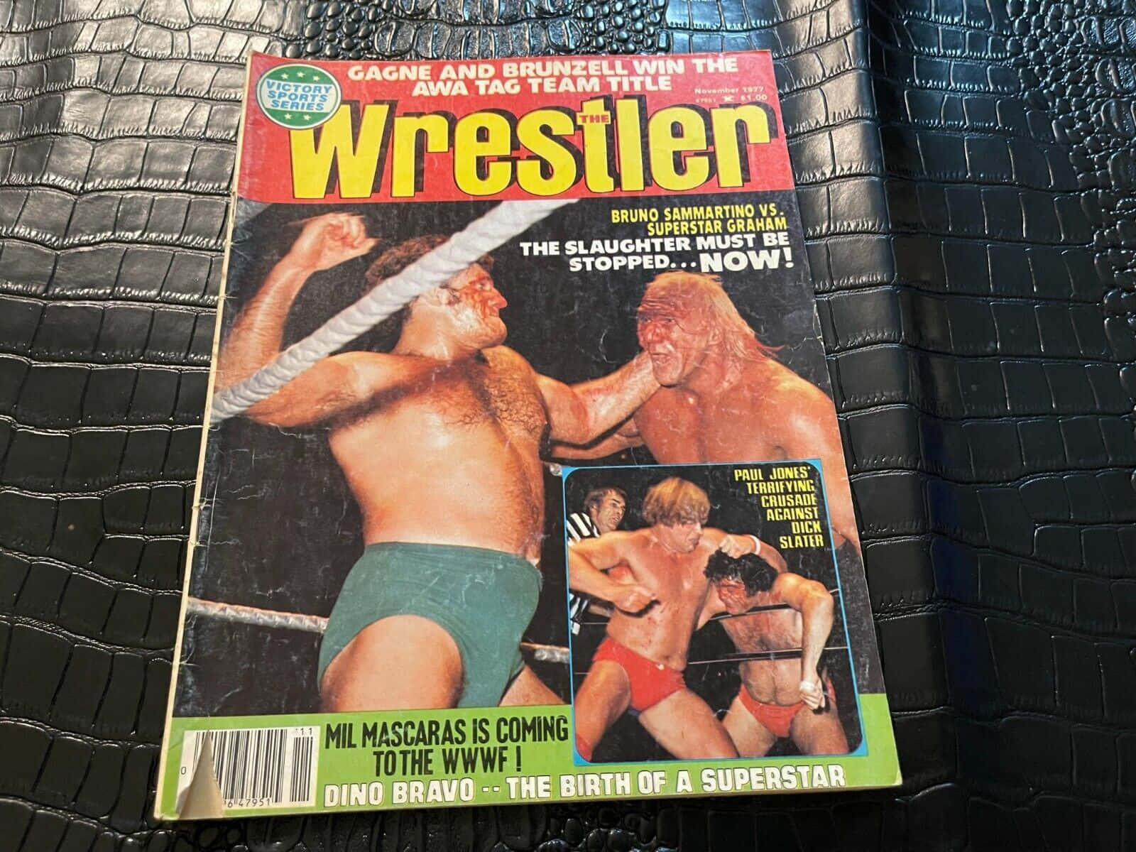 Entertainment 桌布 壁紙 — 復古Wrestler雜誌封面，展示摔角手在擂台上激戰，置於黑色鱷魚紋皮革上。