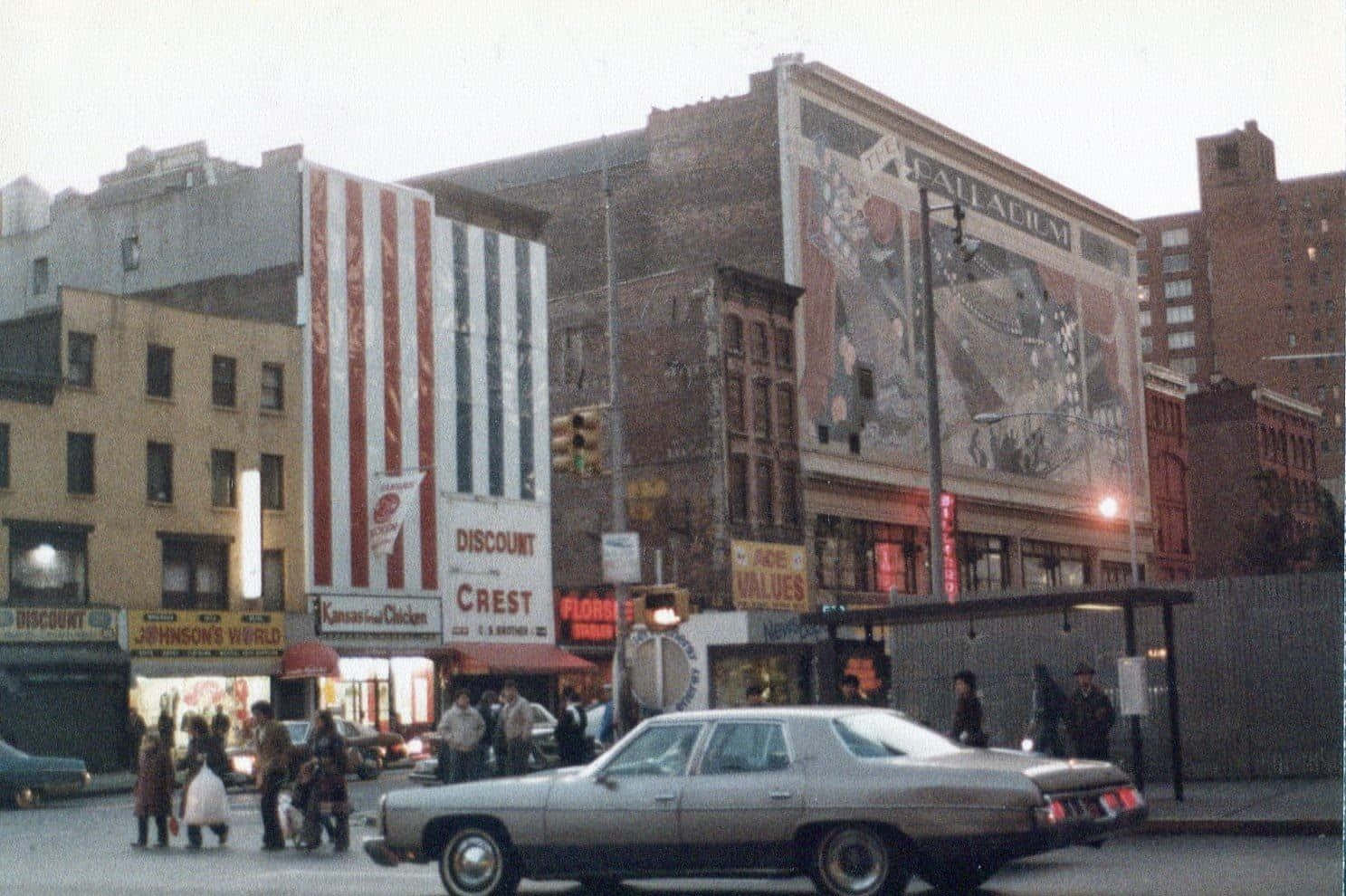 1970s 桌布 壁紙 — 復古城市街景，行人正在銀色轎車附近過馬路，磚砌建築上裝飾著褪色的壁畫和復古標誌。