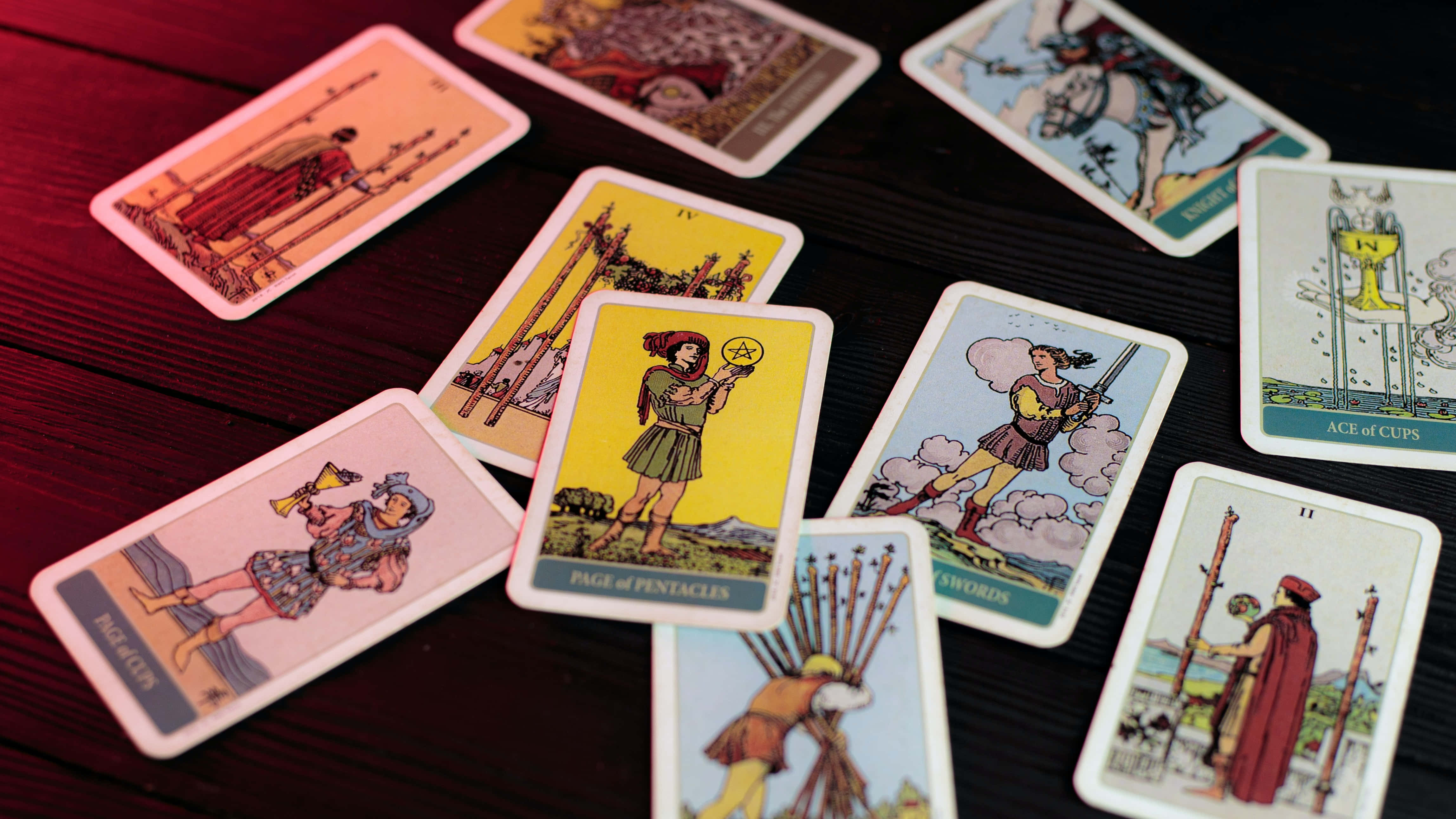 Tarot Card 桌布 壁紙 — 復古塔羅牌散落在深色木桌上，帶有溫暖的環境燈光。