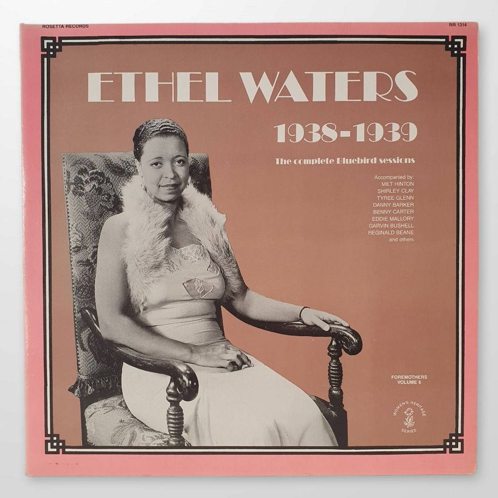 Album Cover 桌布 壁紙 — 復古專輯封面，伊瑟·沃特斯優雅地坐在椅子上，穿著皮草披肩，背景為柔和的粉紅色。