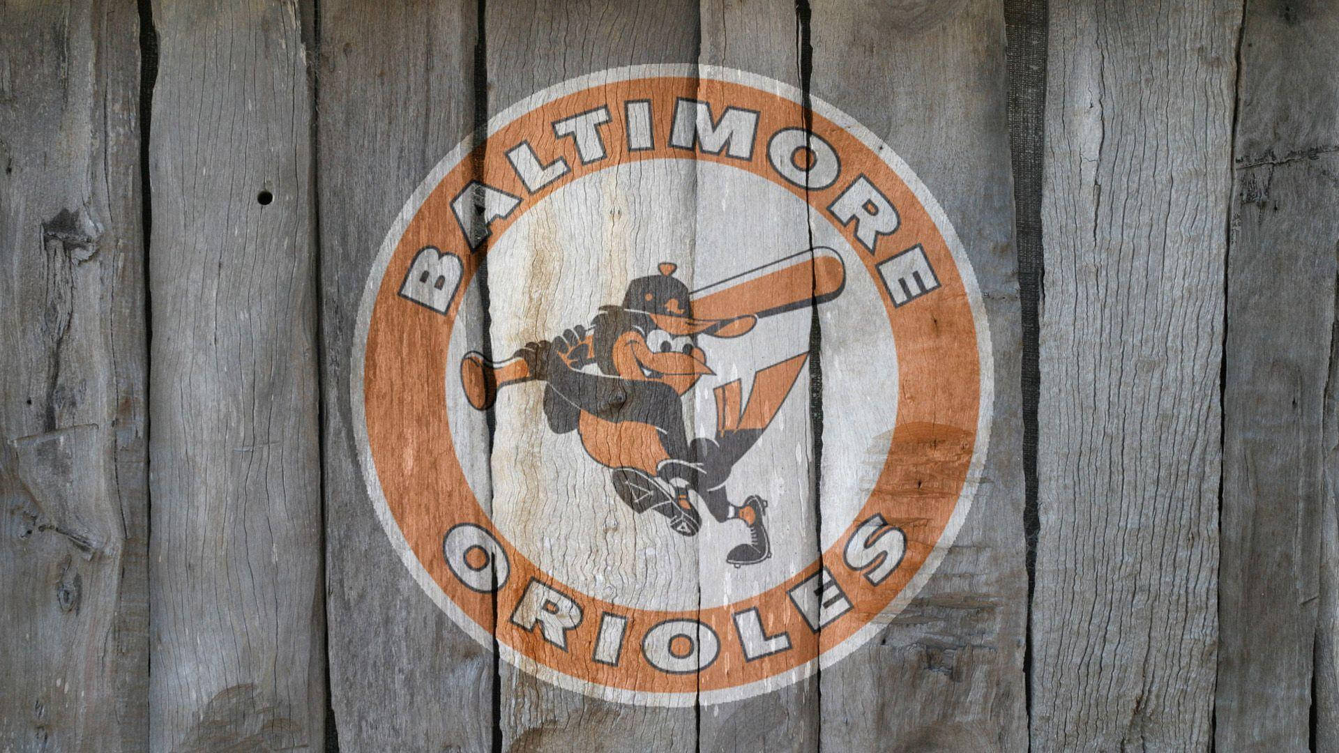 Orioles 桌布 壁紙 — 復古巴爾的摩金鶯棒球標誌，繪於風化灰色木板上，可見木紋與裂縫。