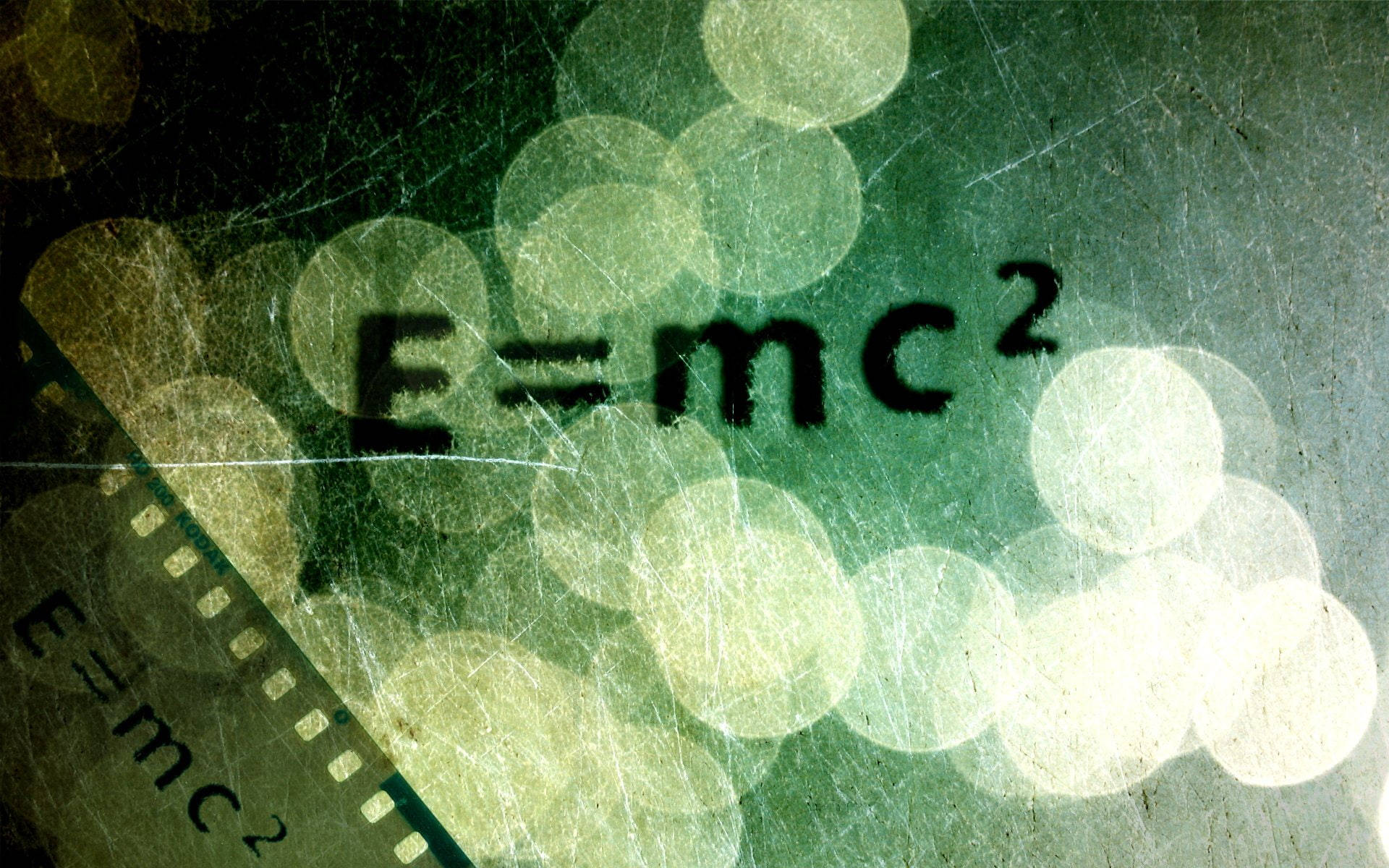 Physics 桌布 壁紙 — 復古底片條，上面疊加了E=mc²公式，背景是綠色散景燈光和刮花紋理。