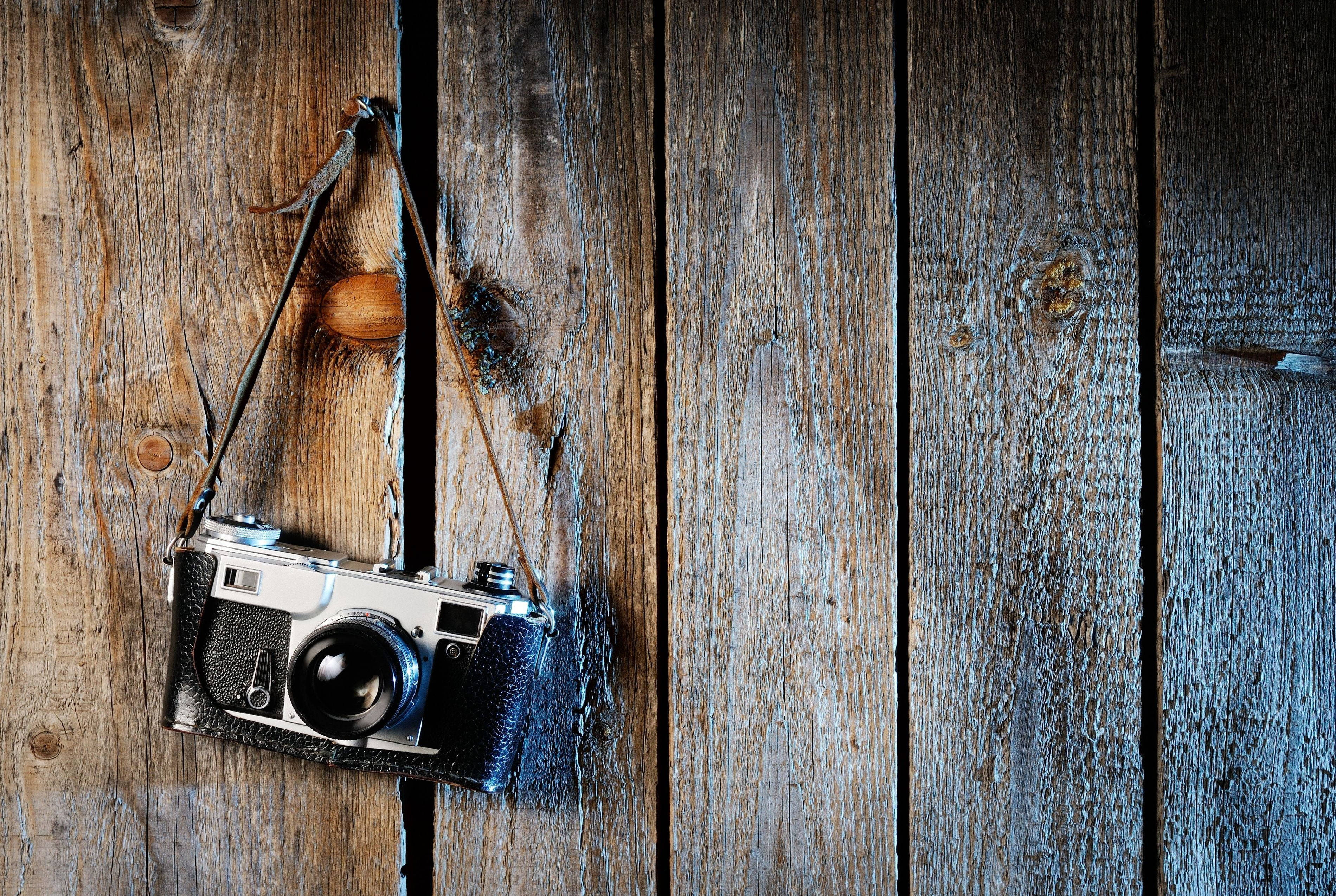Dslr Camera 桌布 壁紙 — 復古底片相機用皮帶掛在風化的木板上，木板紋理豐富，質感古樸。