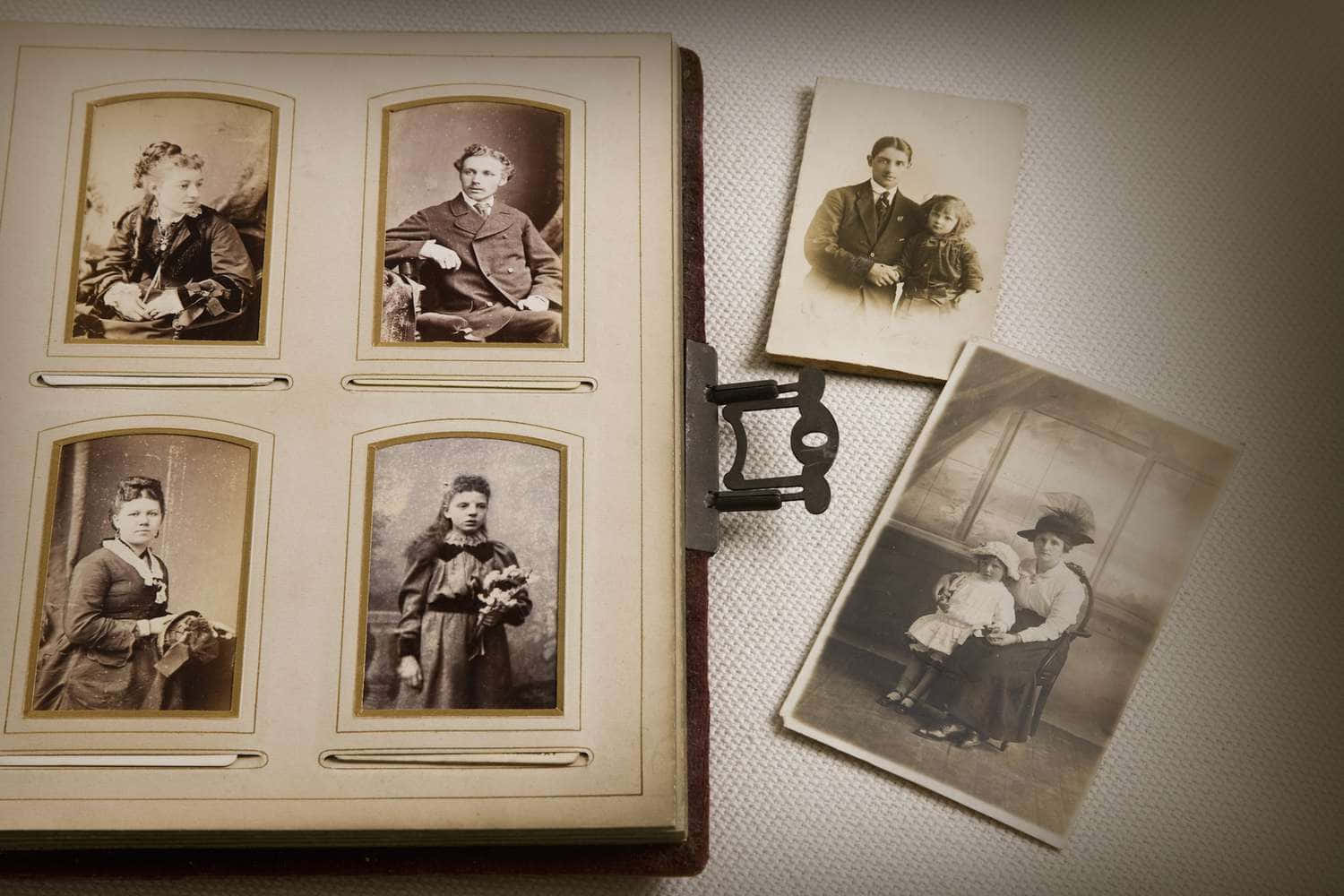 German 桌布 壁紙 — 復古懷舊的sepia色調家庭肖像，放在古董相簿裡，周圍散落著一些照片在有紋理的布料上。