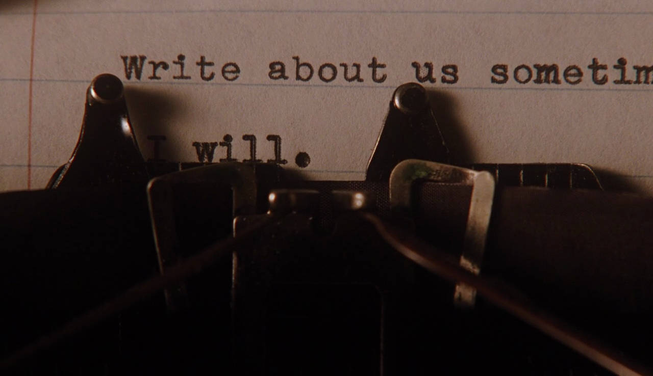 A 桌布 壁紙 — 復古打字機的特寫，在昏暗燈光下打出「Write about us sometime. I will.」字句。