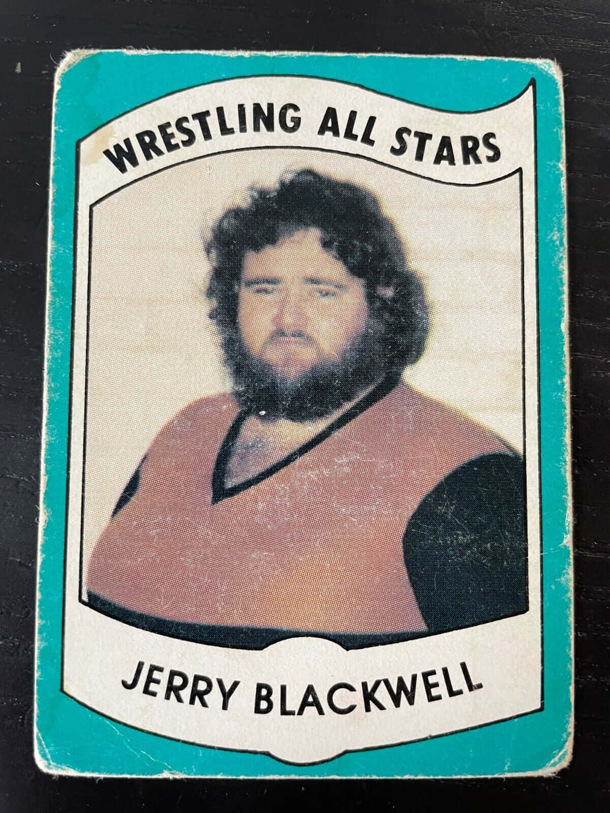 card 桌布 壁紙 — 復古摔角收藏卡， featuring Jerry Blackwell 捲髮和鬍鬚，身穿棕色和黑色背心，背景為青綠色邊框。