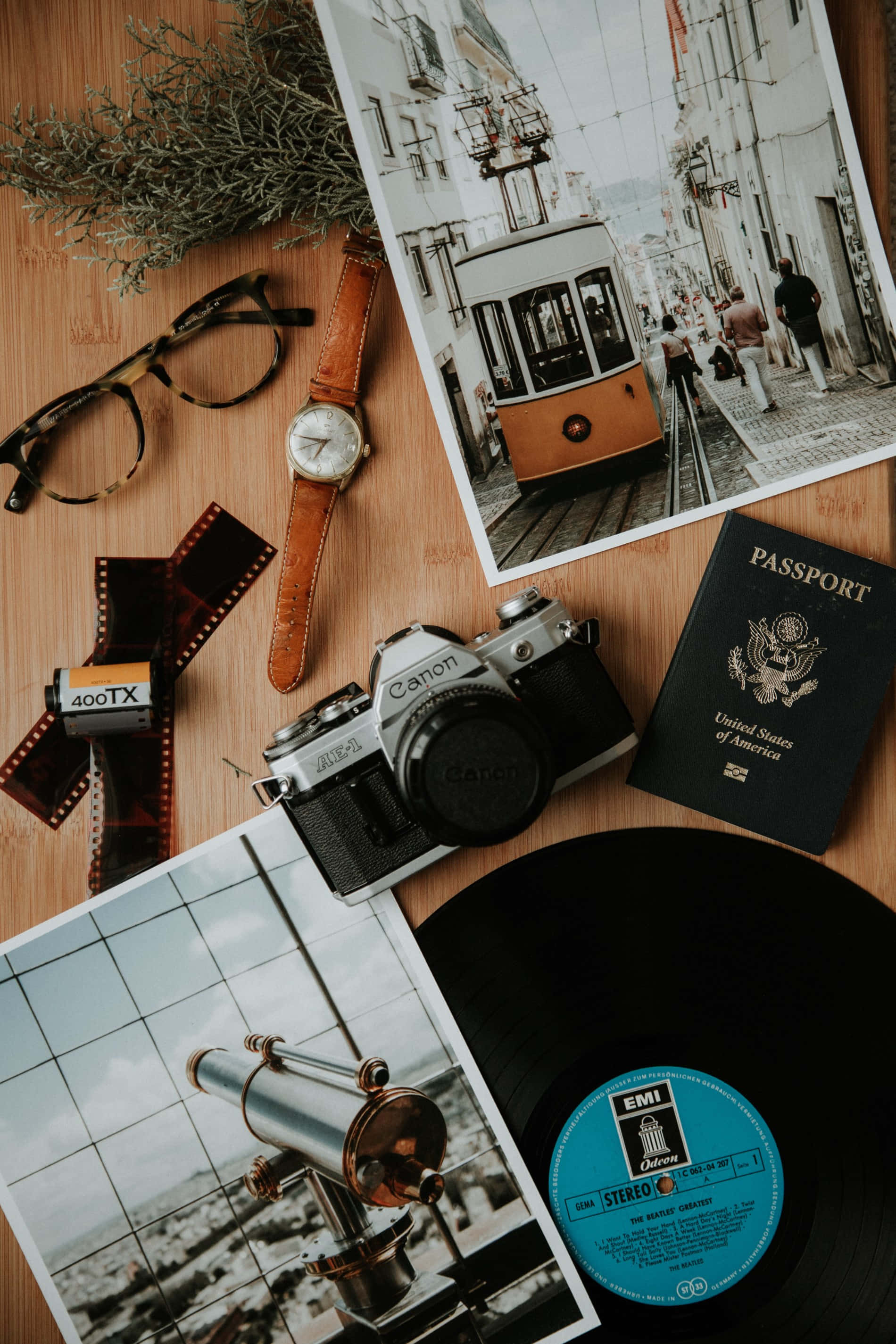 Travel Aesthetic Phone 桌布 壁紙 — 復古旅行物品包括Canon相機、護照、底片捲和黑膠唱片，排列在木質表面上。
