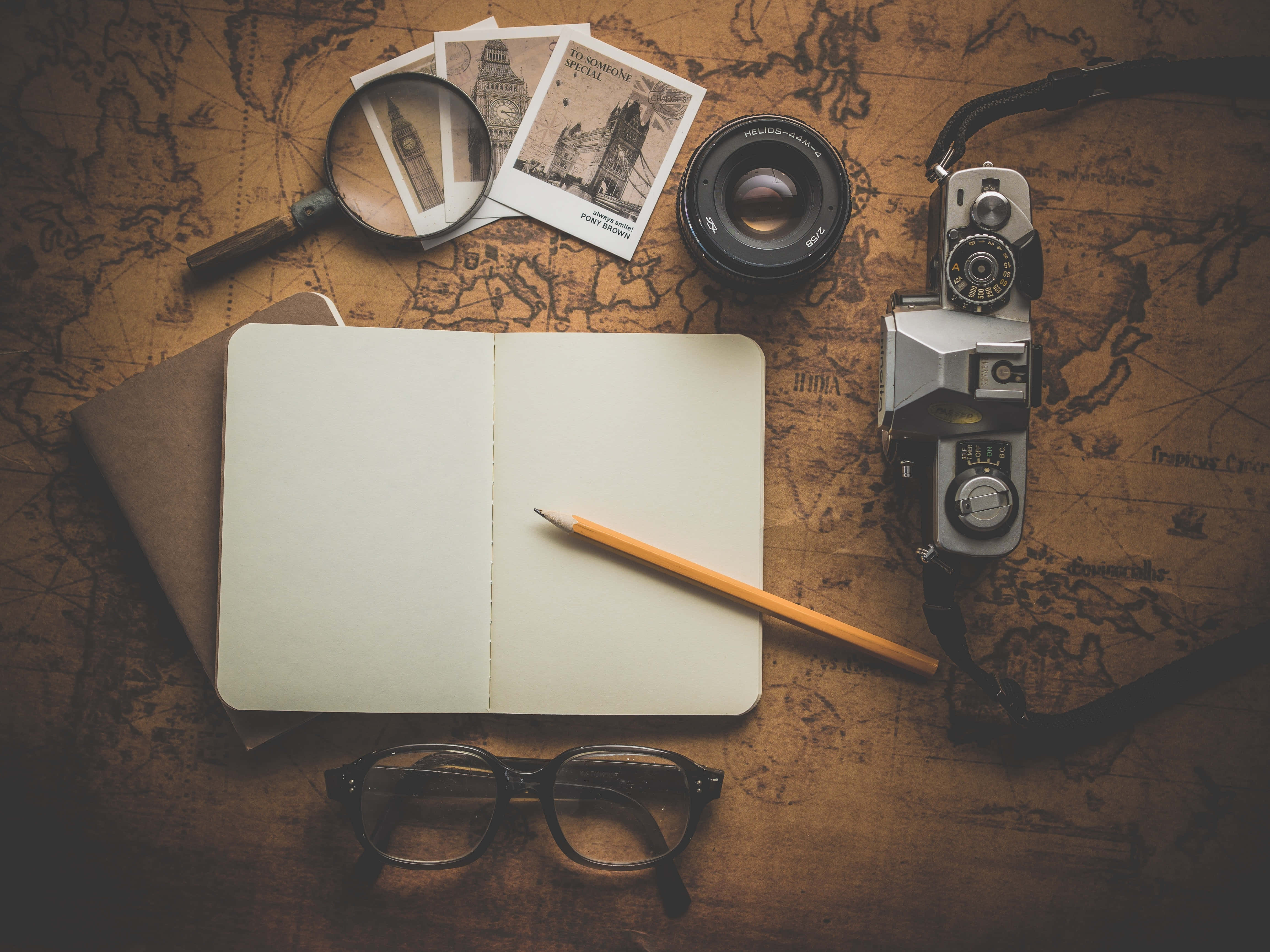 Notebook 桌布 壁紙 — 復古旅行裝備，包括相機、放大鏡和筆記本，放在一張古董世界地圖上。