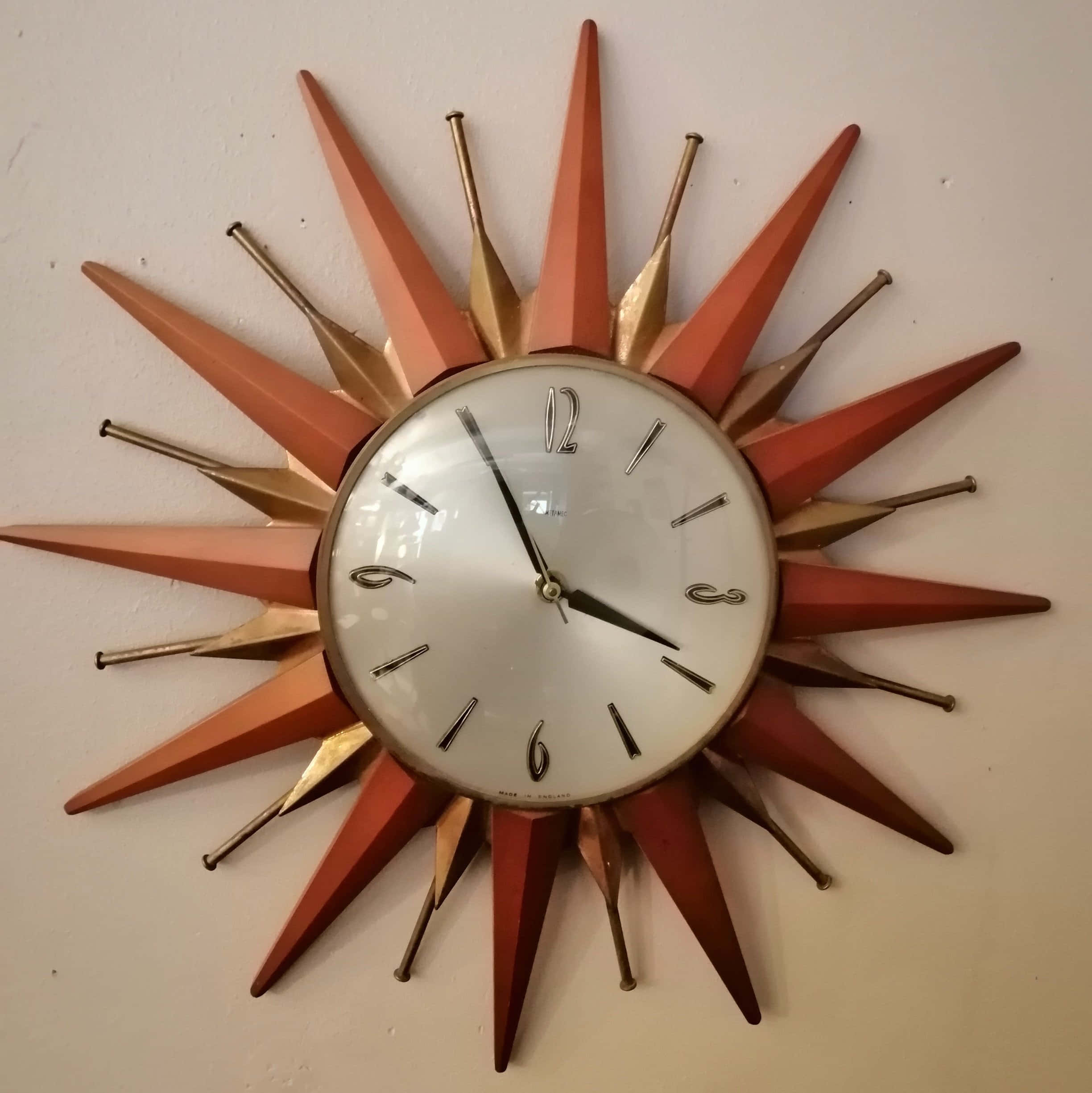 Wall Clock 桌布 壁紙 — 復古旭日紋掛鐘，橙色和金色尖刺從白色鐘面放射而出，搭配黑色指針和數字。