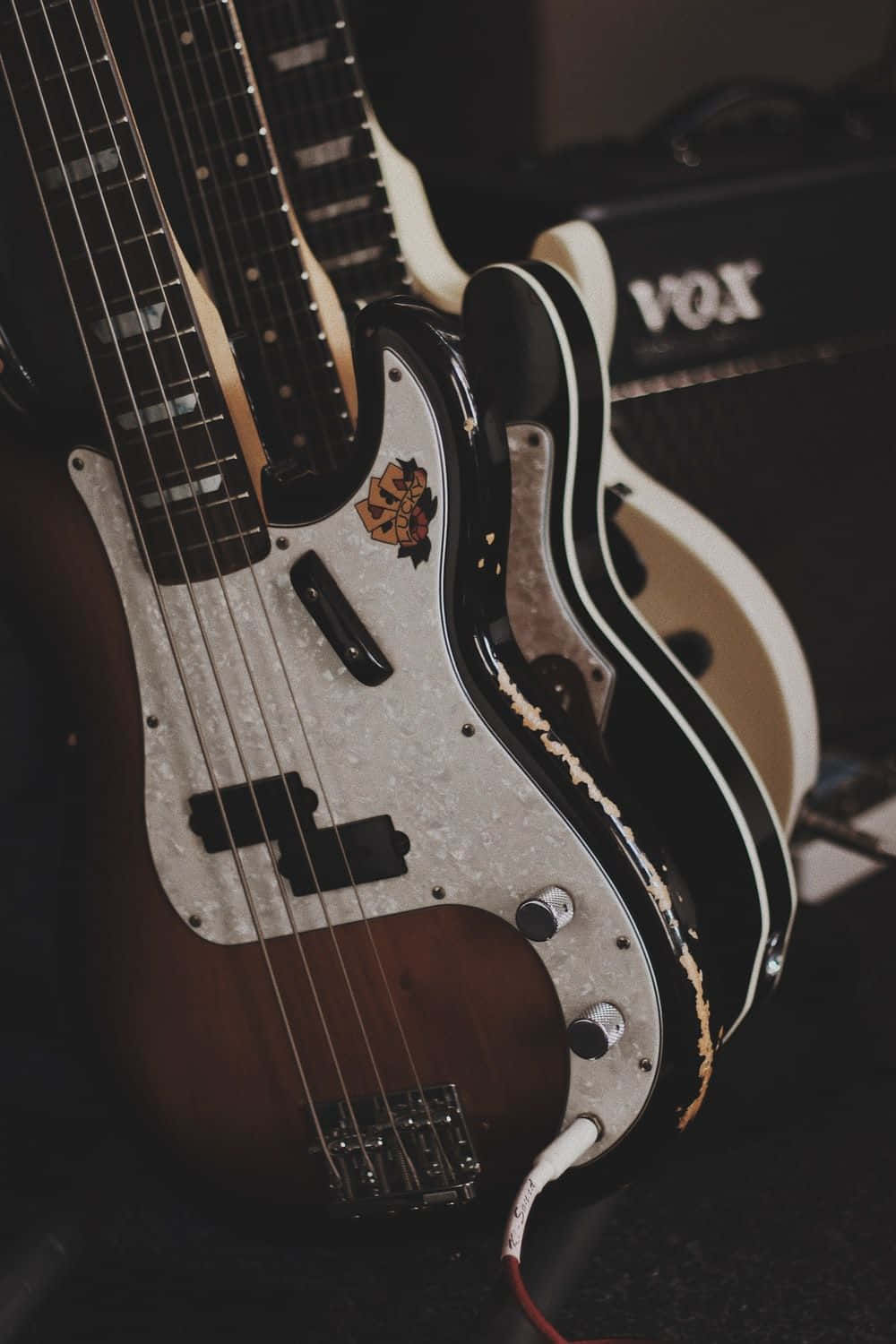 Guitar Aesthetic 桌布 壁紙 — 復古旭日紋貝斯吉他特寫，帶有磨損的護板和背景中的Vox音箱。
