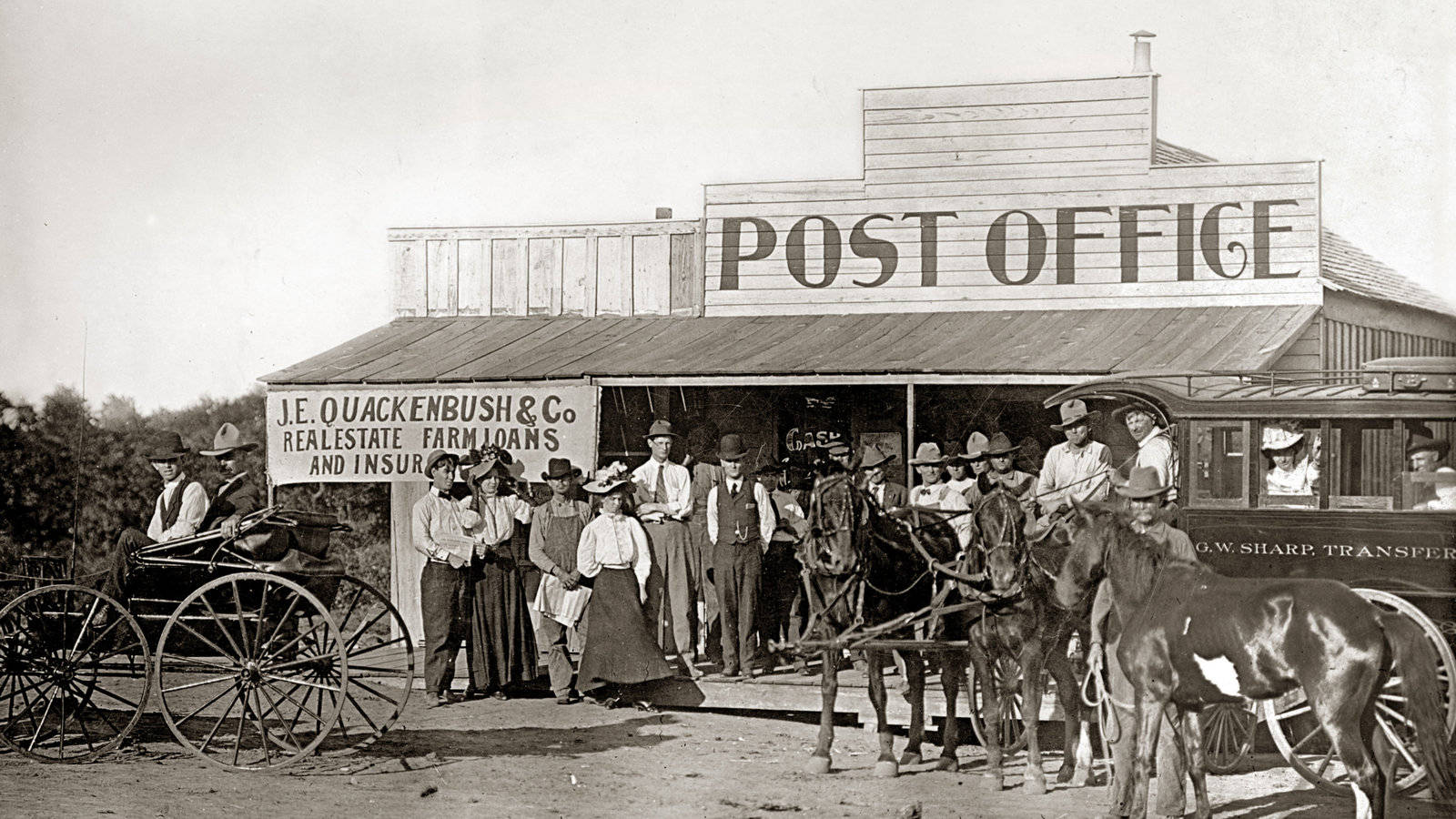 Post Office 桌布 壁紙 — 復古棕褐色照片，人們和馬車聚集在一個帶有房地產標誌的木製郵局外。