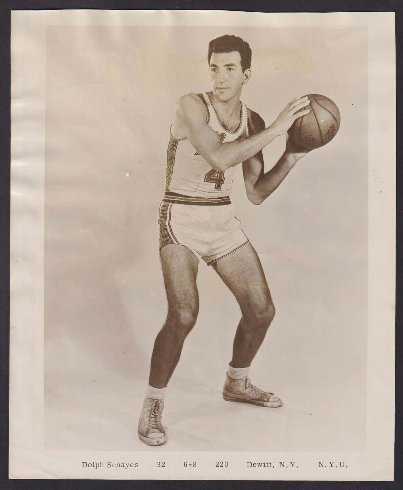 桌布 壁紙 — 復古棕褐色調工作室肖像，籃球運動員Dolph Schayes身穿N.Y.U.制服，以平衡姿勢持球。