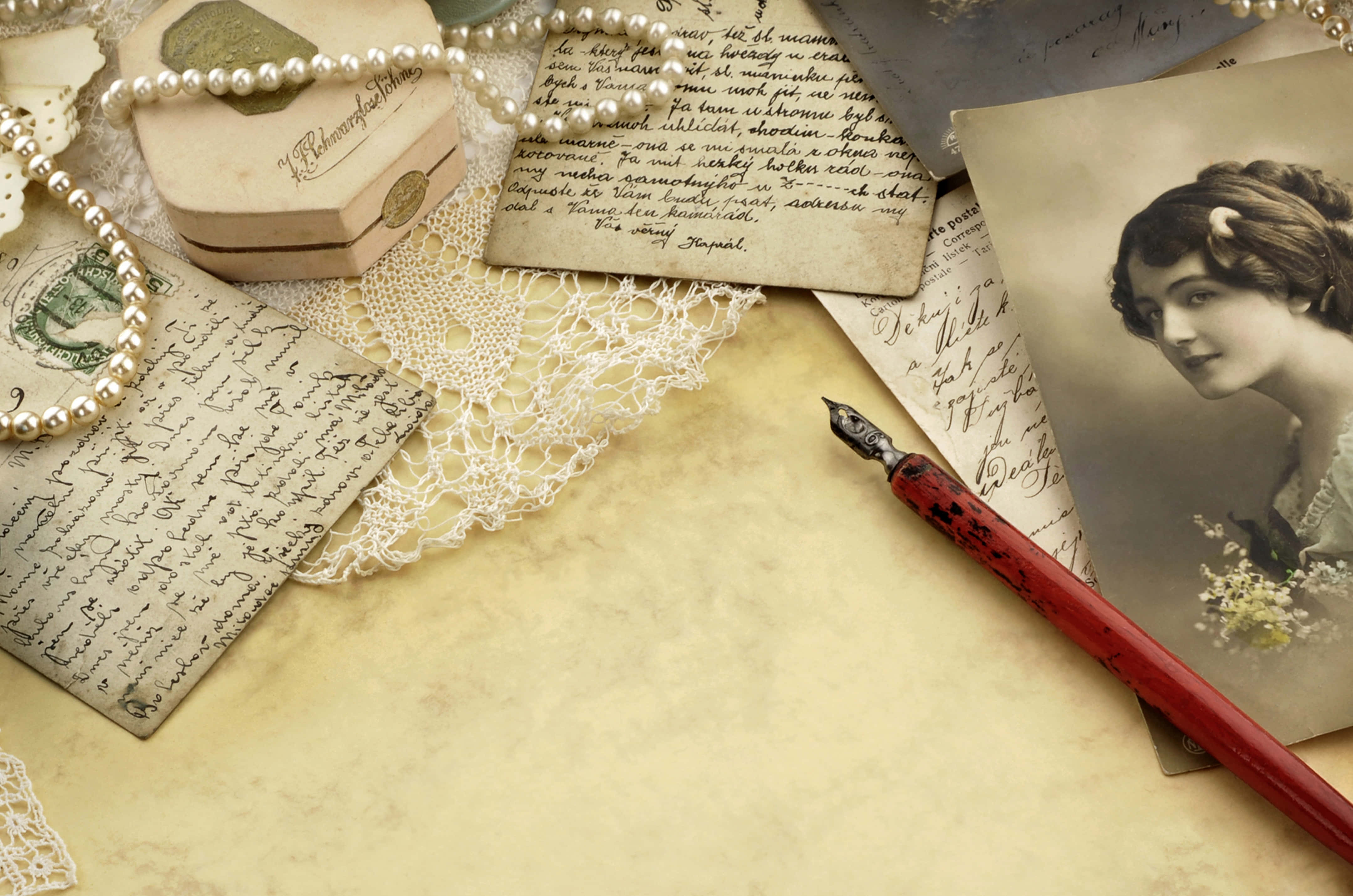 Letter 桌布 壁紙 — 復古棕褐色調照片，一位女士旁邊有手寫信件、蕾絲、珍珠和一支紅色鋼筆，放在舊紙上。