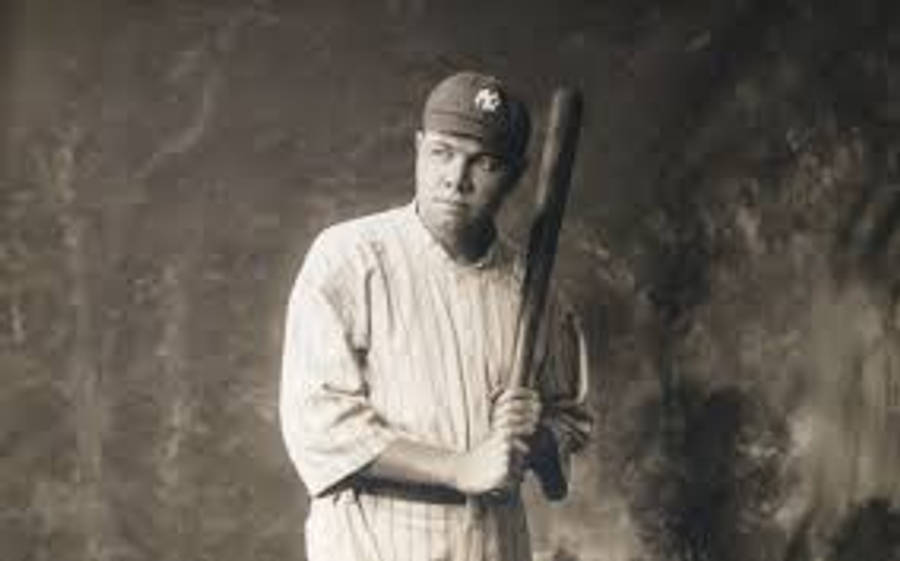 Babe Ruth 桌布 壁紙 — 復古棕褐色調肖像，一名身穿條紋球衣的棒球運動員在紋理背景前手持球棒。