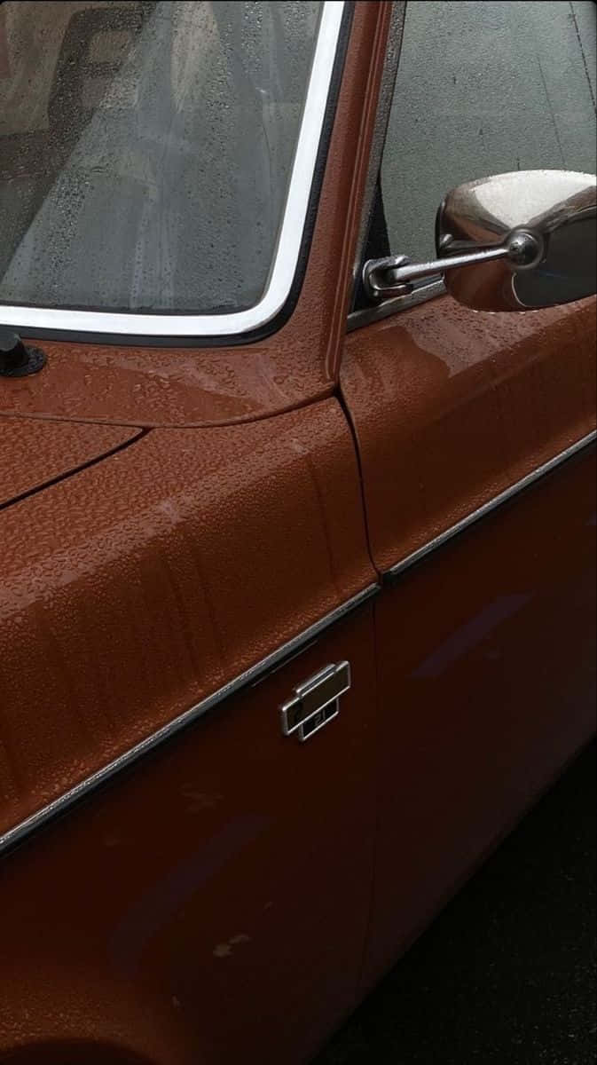 Minimalist Car 桌布 壁紙 — 復古生鏽橙色車門的特寫，表面有閃閃發光的雨滴和鍍鉻飾條。