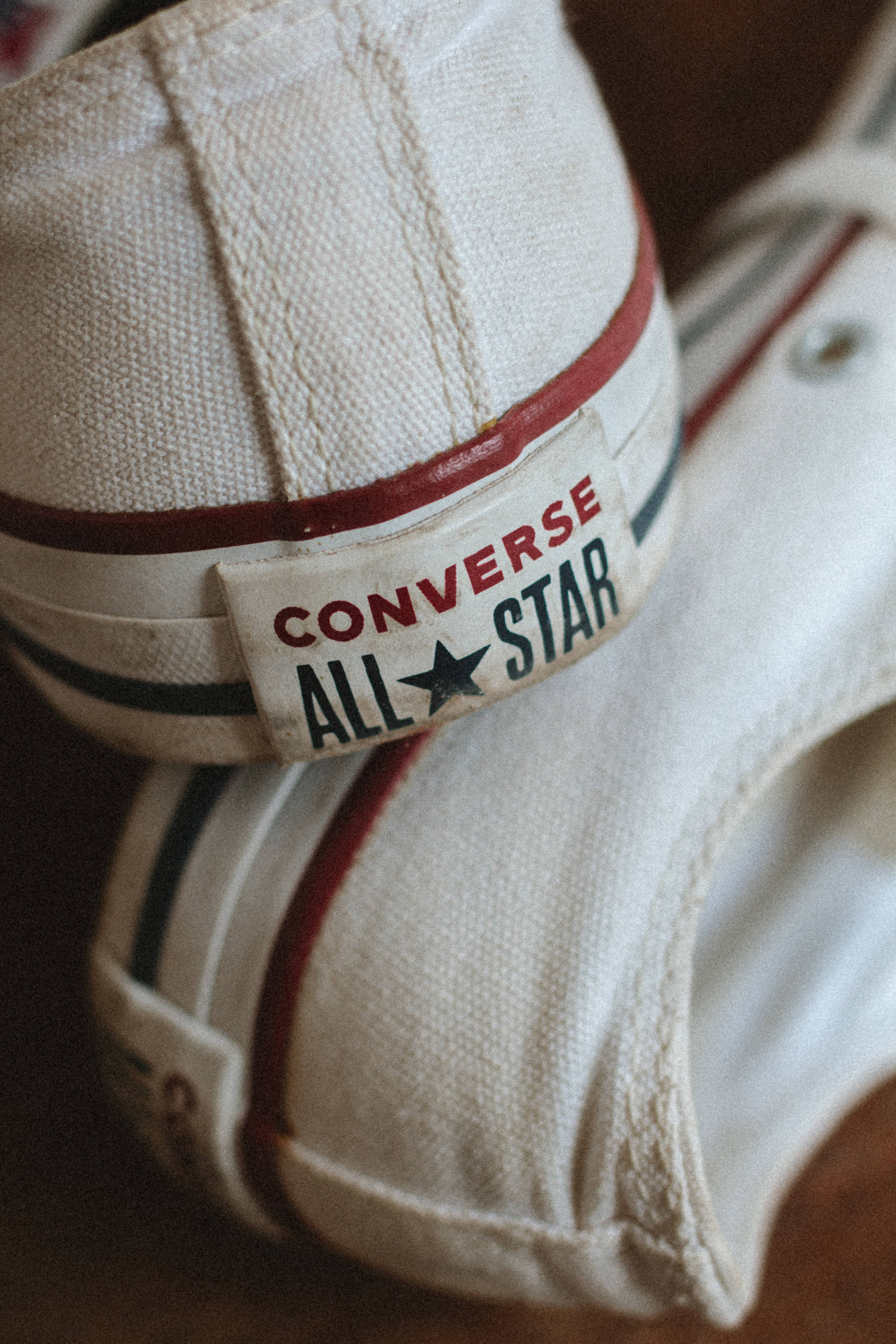 Converse 桌布 壁紙 — 復古白色Converse All Star運動鞋特寫，帶有紅色和黑色條紋，顯示磨損質感和經典品牌標誌。