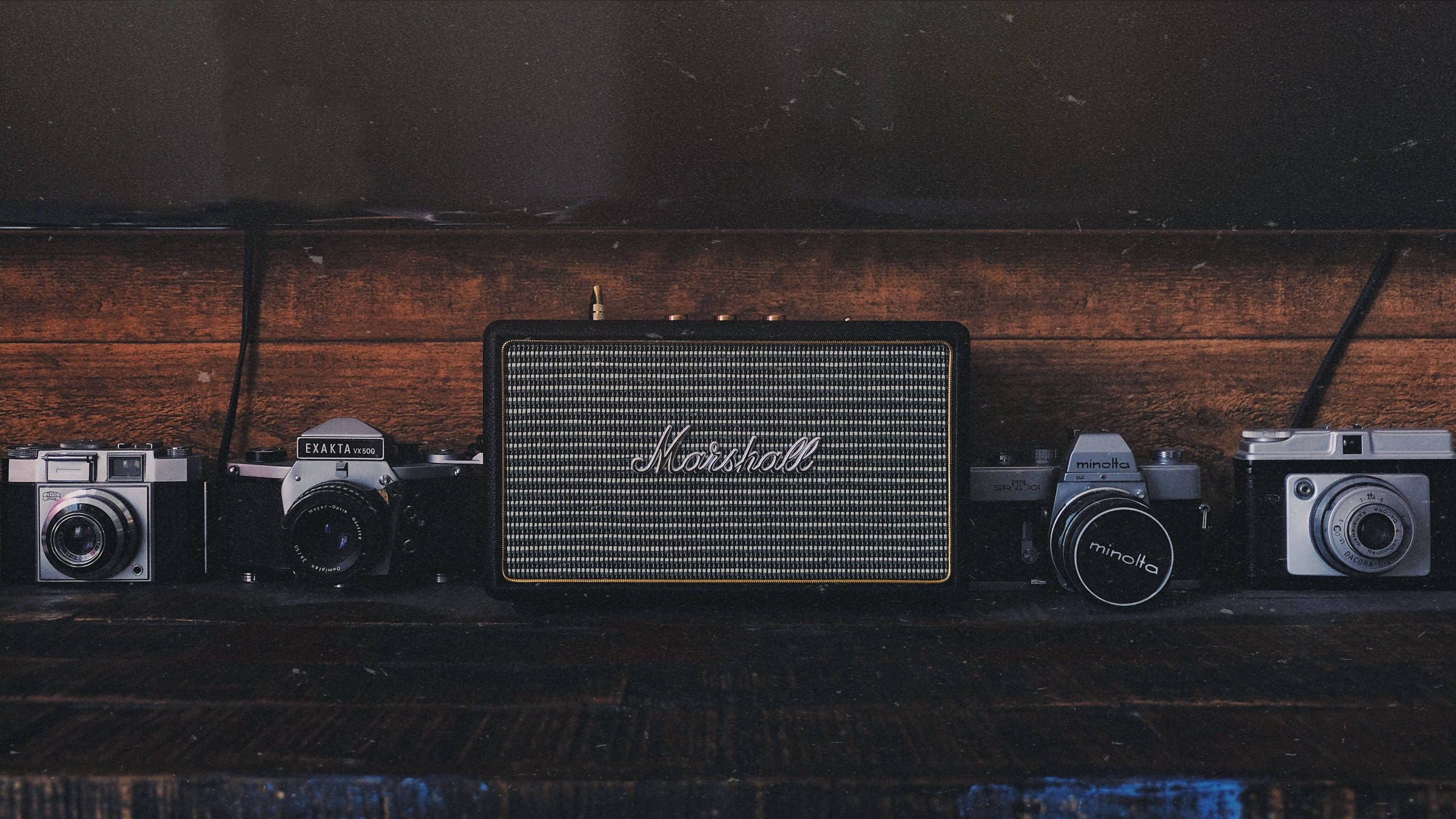 Marshall 桌布 壁紙 — 復古相機在氣氛燈光下，於質樸木架上圍繞著 Marshall 揚聲器。