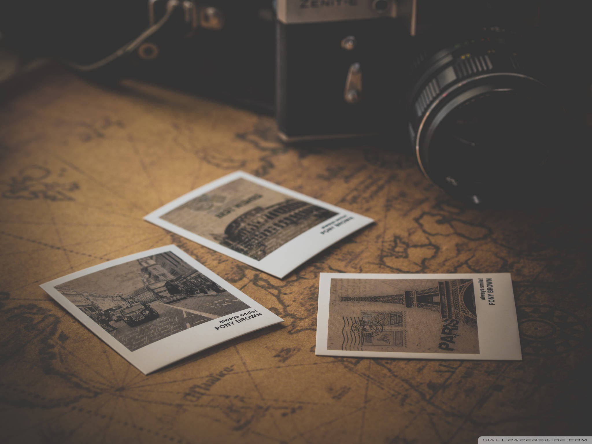 Travel Desktop 桌布 壁紙 — 復古相機放在一張陳舊的世界地圖上，旁邊是巴黎地標的懷舊旅行照片。
